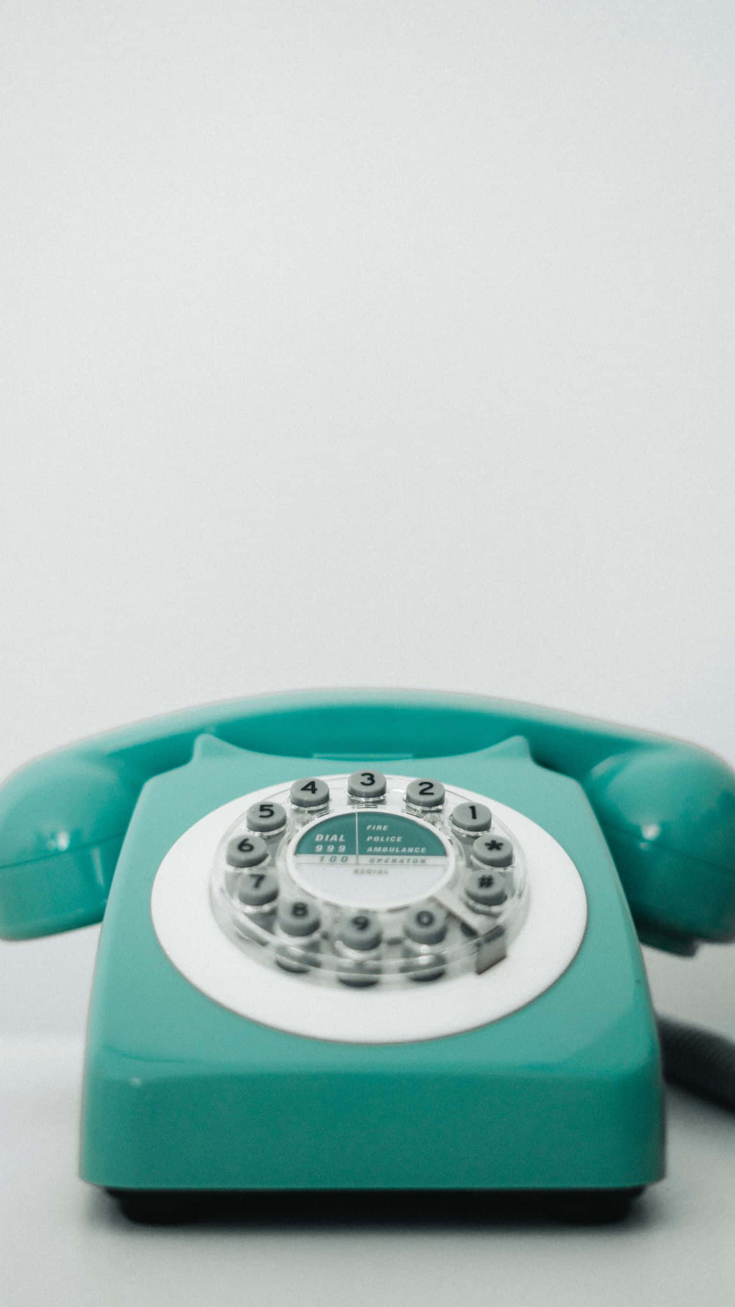 Retro Phone 桌布 壁紙 — 一部復古青綠色轉盤電話，帶有白色撥號盤，居中放置在純白色背景上。