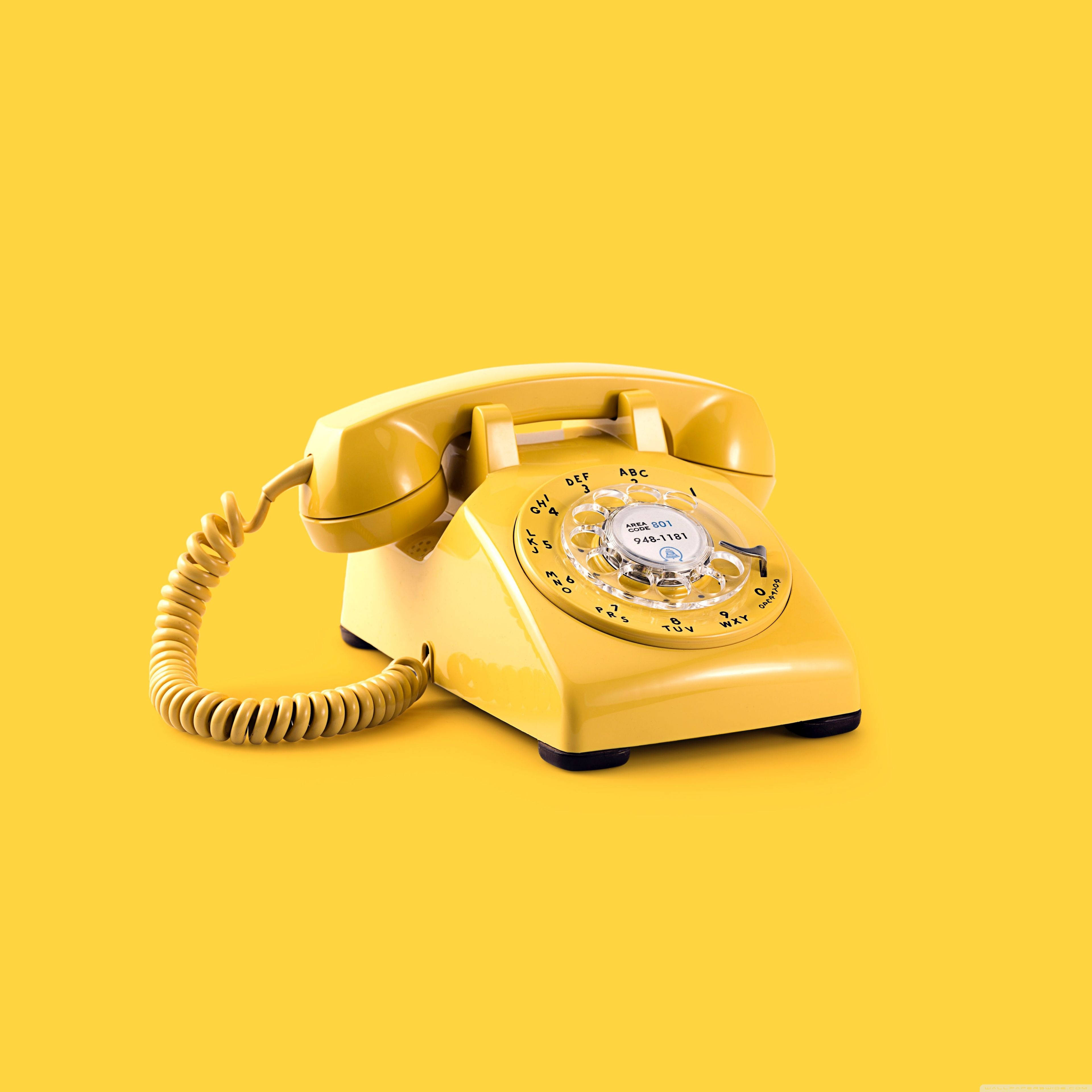 Aesthetic Retro 桌布 壁紙 — 一部復古黃色轉盤電話靠在純黃色背景上，帶有柔和陰影。