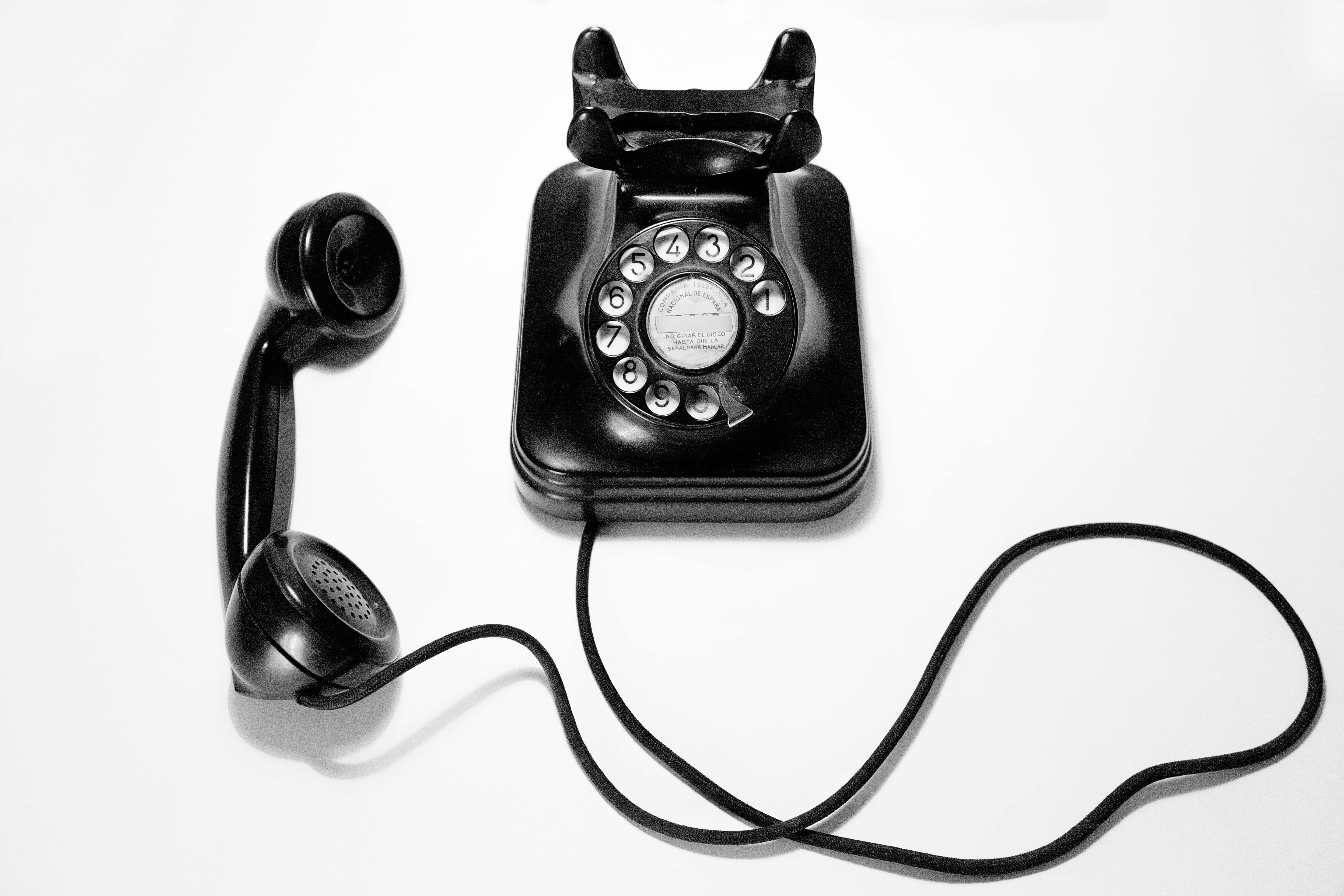 Phone Call 桌布 壁紙 — 一部復古黑色轉盤電話，聽筒放在旁邊，背景為純白色。