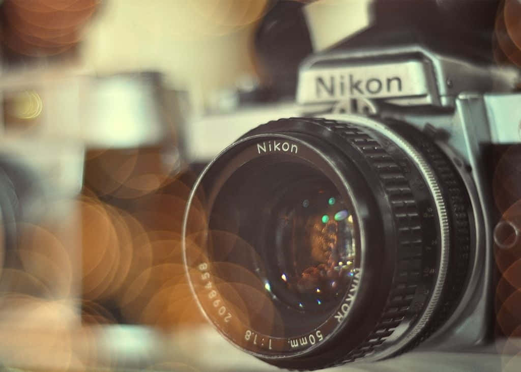攝影 桌布 壁紙 — 一部懷舊Nikon相機，配備50mm鏡頭，在柔和對焦下，背景是溫暖的散景。