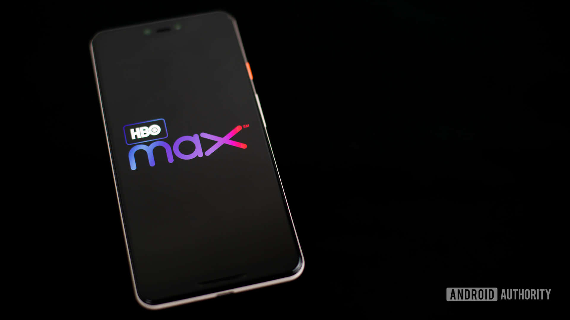 HBO 桌布 壁紙 — 一部時尚的智慧型手機在黑色背景上顯示鮮豔的HBO Max標誌，柔和的光線突出其邊緣。