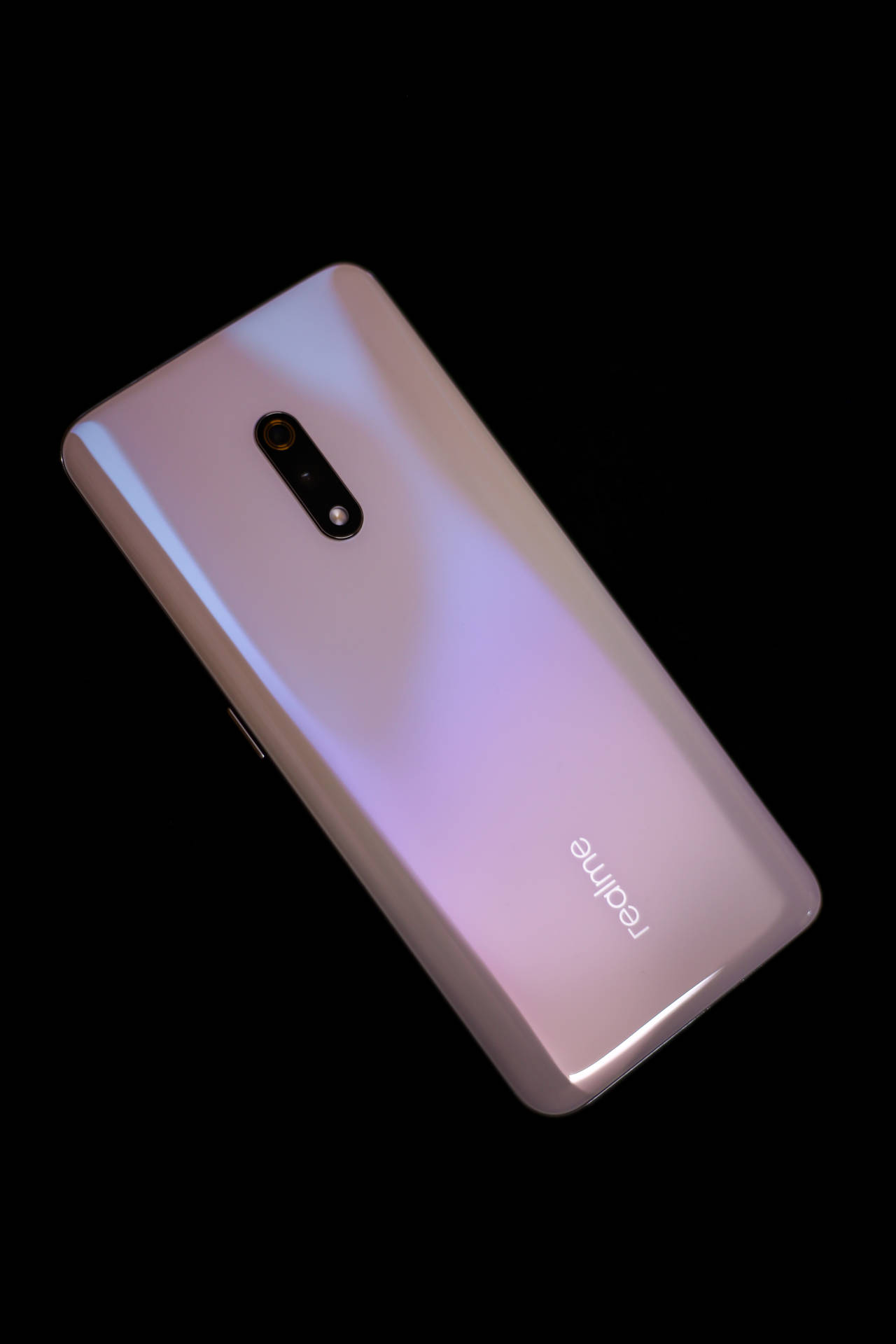 黑色背景上的粉紅色漸變 realme 智慧型手機。