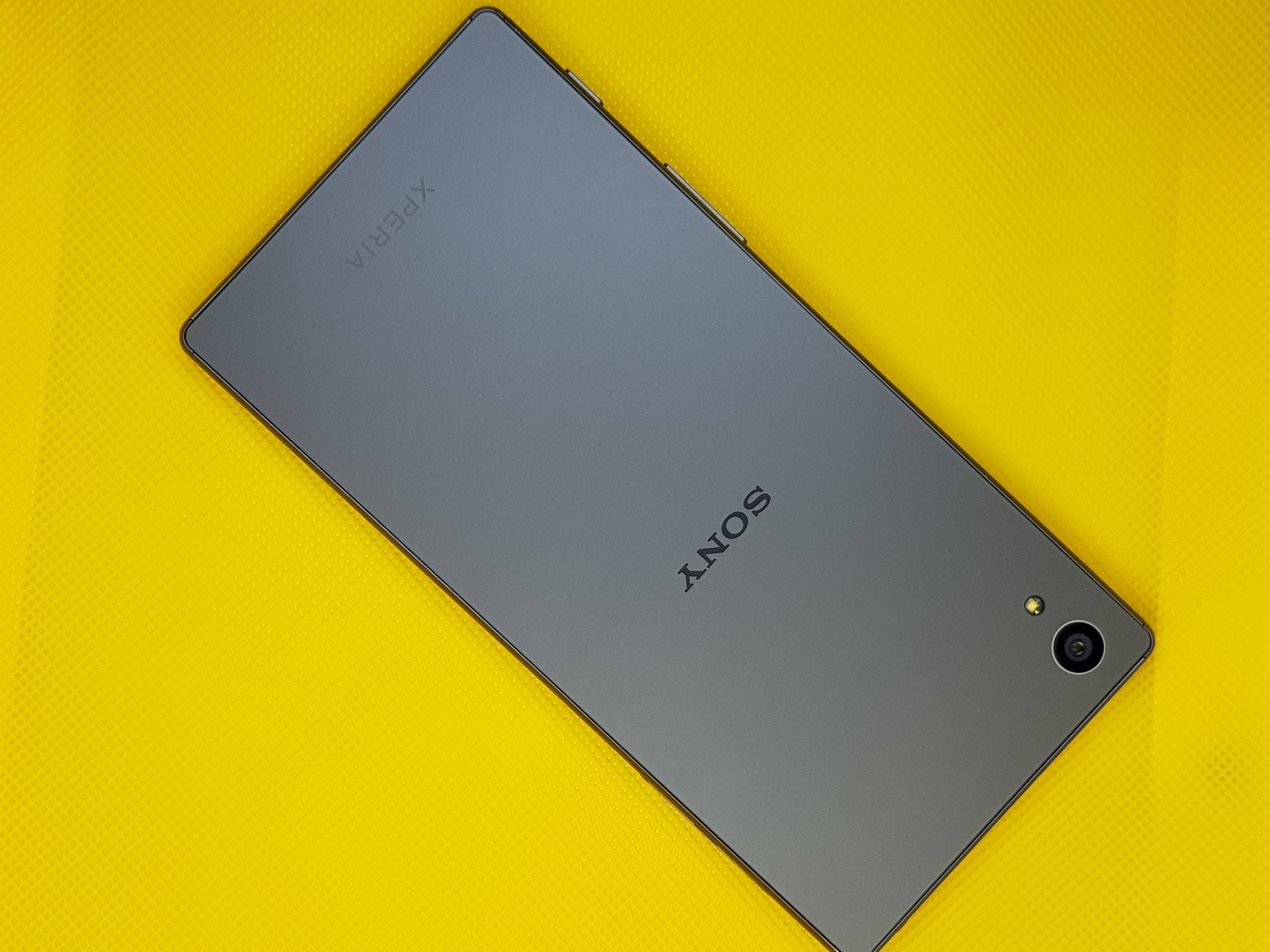 Sony 桌布 壁紙 — 一部時尚的灰色Sony Xperia智慧型手機對角放置在充滿活力的黃色紋理表面上。