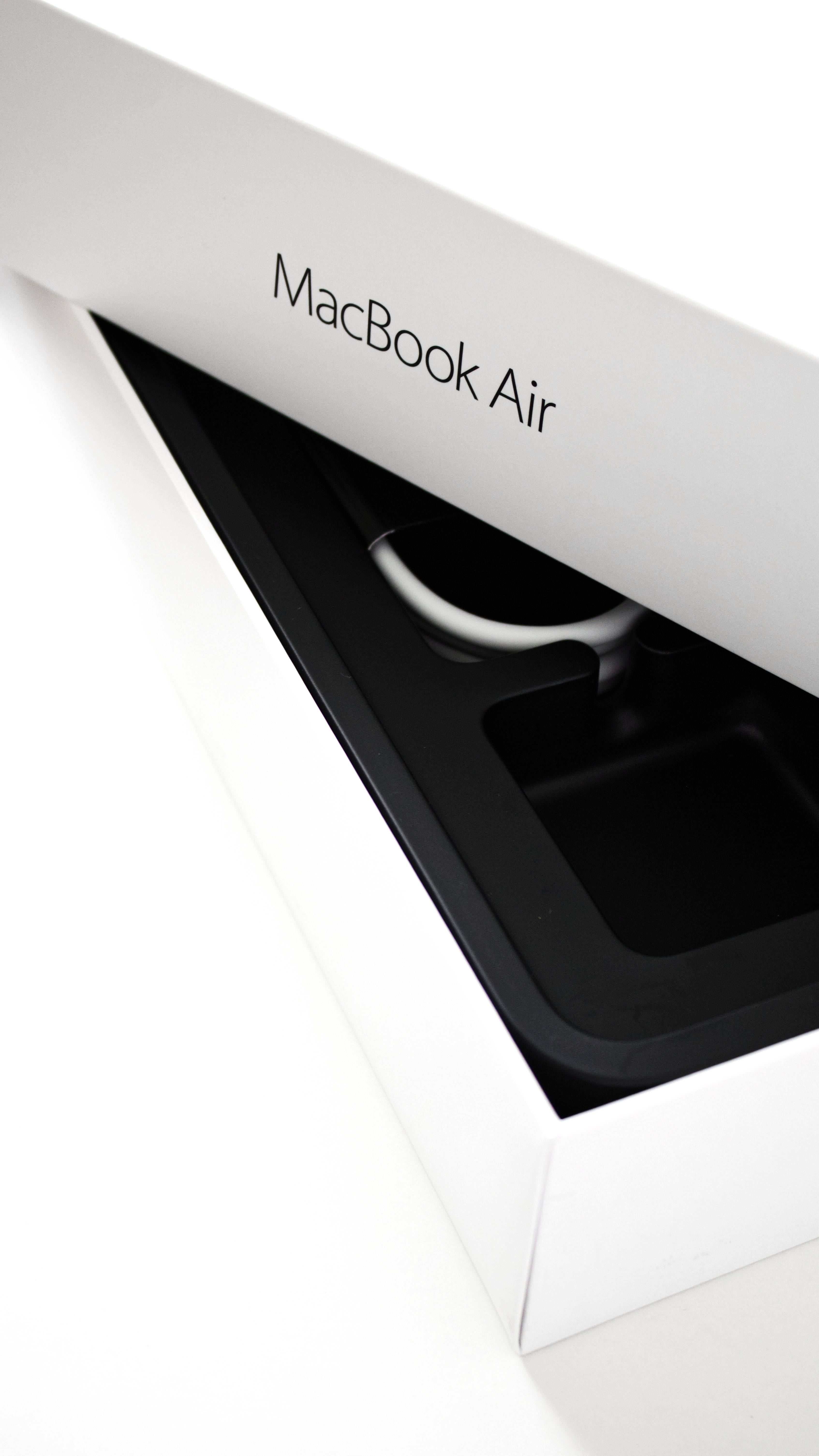 Macbook Air 2020 桌布 壁紙 — 一部時尚的白色 MacBook Air 從其簡約的白色盒子中部分露出，展現黑色內部及銀色電線。