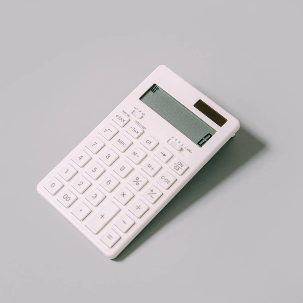 計算機 桌布 壁紙 — 一部時尚的白色計算機以傾斜角度放置在柔和的灰色表面上，投下柔和的陰影。