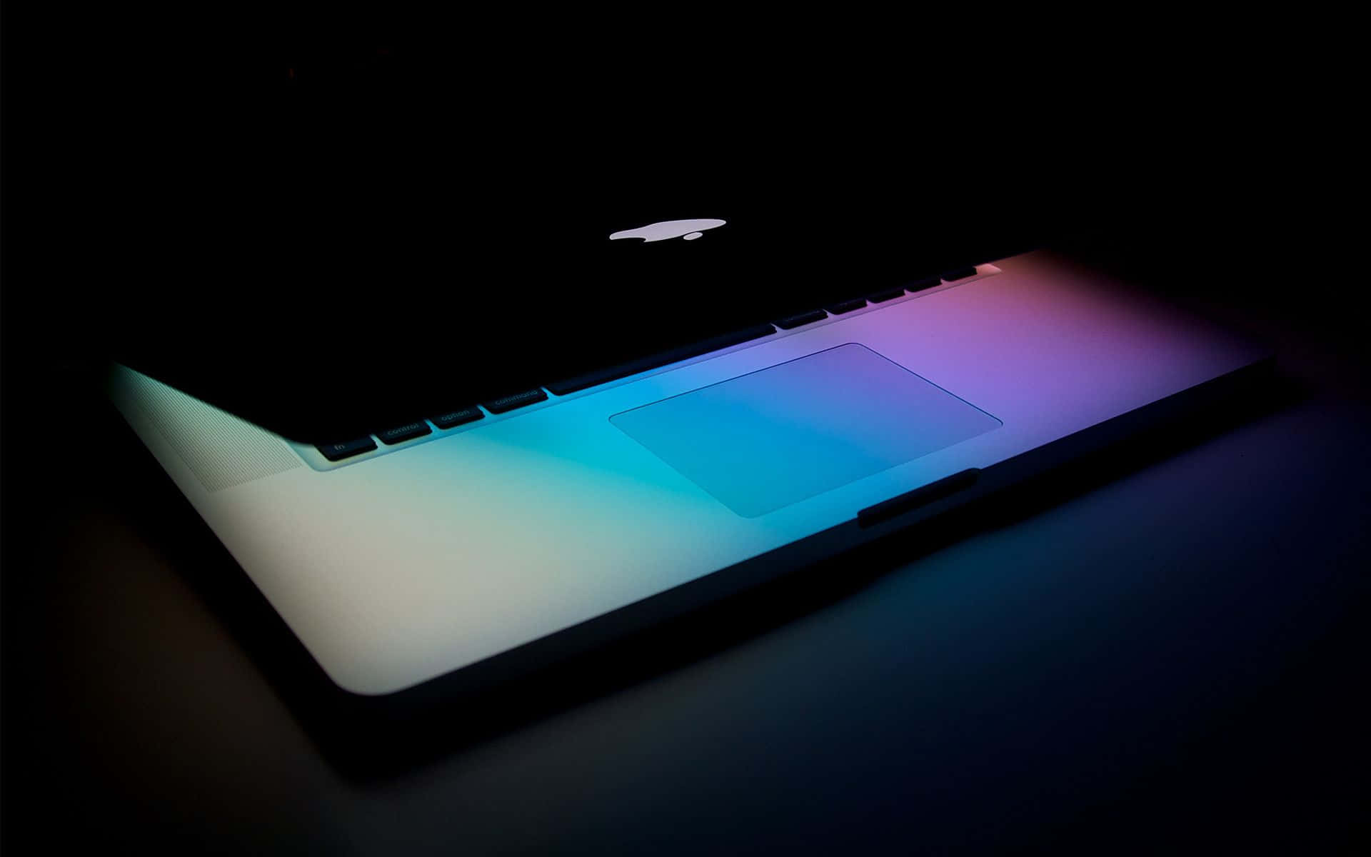 Macbook Retina 桌布 壁紙 — 一部時尚的筆記型電腦在漆黑背景下散發出鮮豔的藍色和紫色背光。