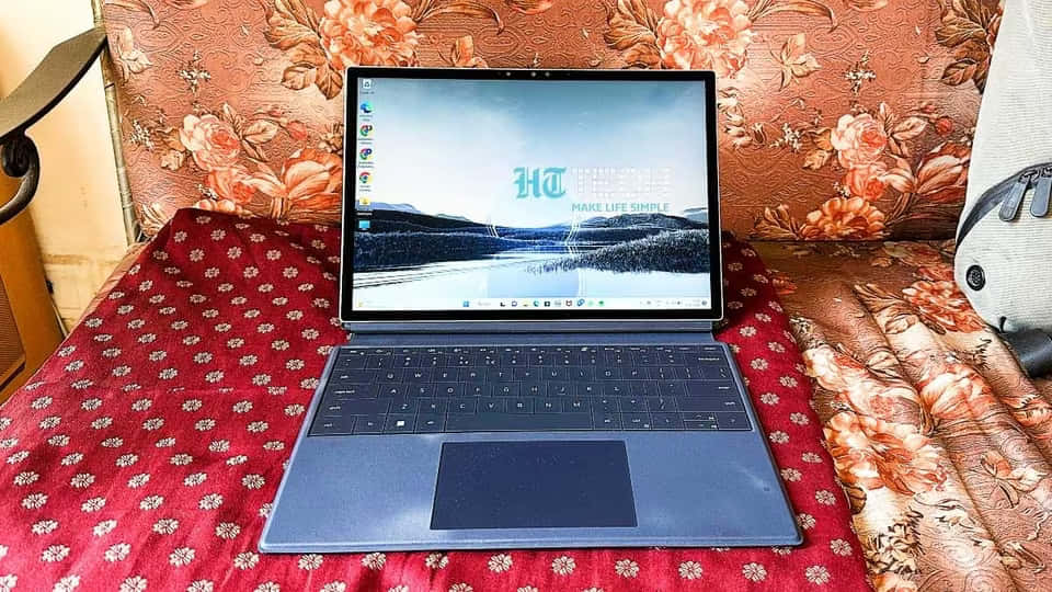 Dell 桌布 壁紙 — 一部時尚的筆記型電腦打開放在紅色圖案床罩上，背景是花卉軟墊床頭板。