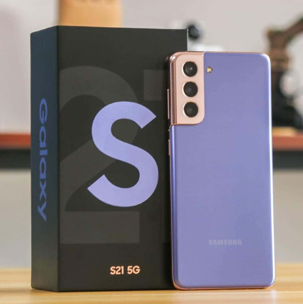 Galaxy S10 桌布 壁紙 — 一部時尚的薰衣草色Samsung Galaxy S21 5G智慧型手機站在木質表面上，旁邊是它的黑色盒子。