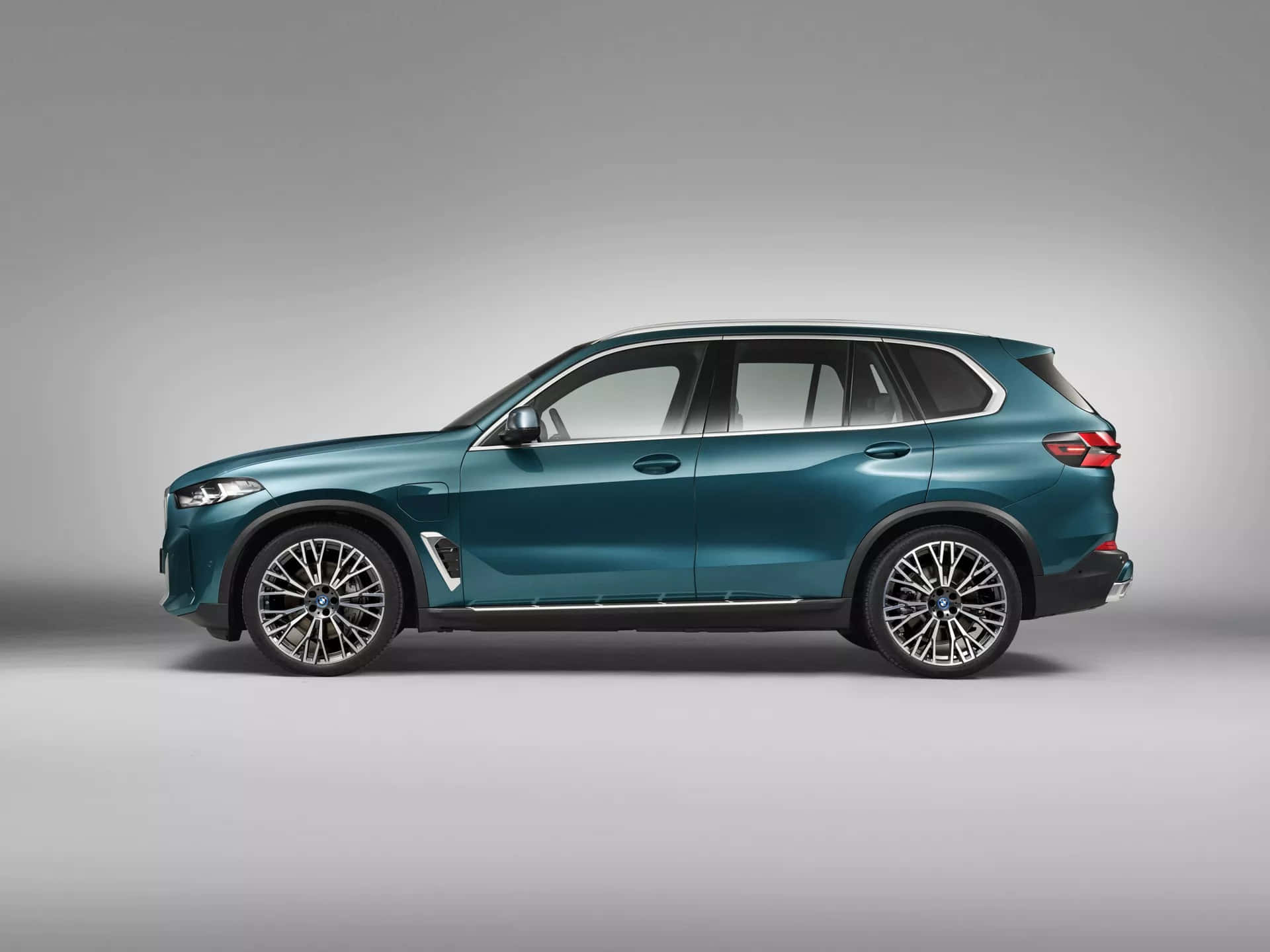 Bmw X5 桌布 壁紙 — 一部時尚的藍綠色BMW X5 SUV，以側面輪廓展示在極簡灰色工作室背景前。