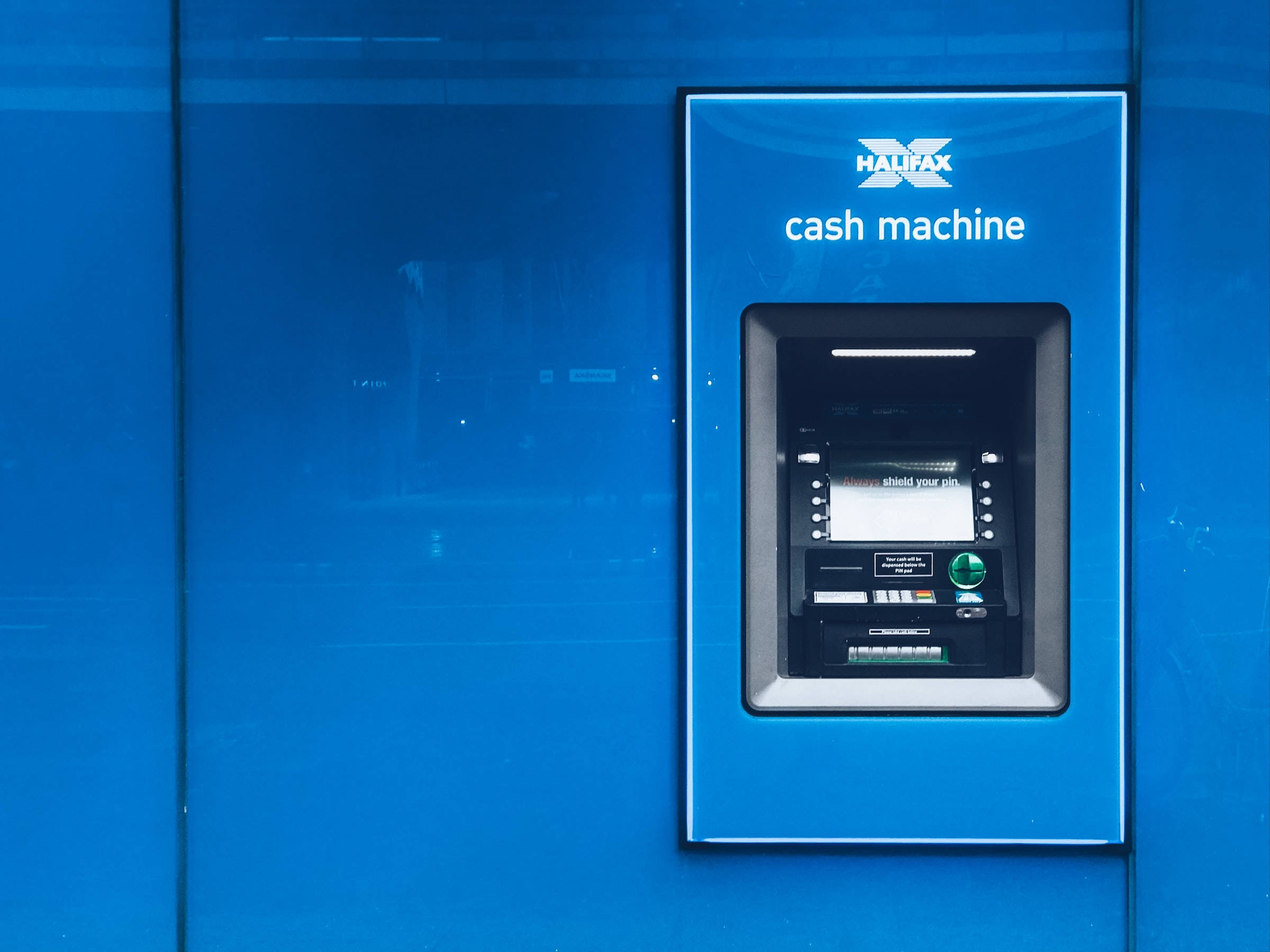 atm 桌布 壁紙 — 一部時尚的藍色 Halifax 提款機嵌入在相配的藍色玻璃牆中，帶有反射表面。