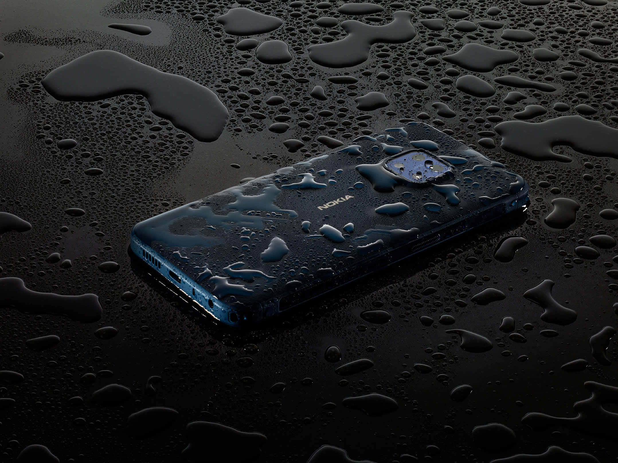 諾基亞 桌布 壁紙 — 一部時尚的藍色 Nokia 手機放在黑暗潮濕的表面上，閃爍的水滴反射著環境光。