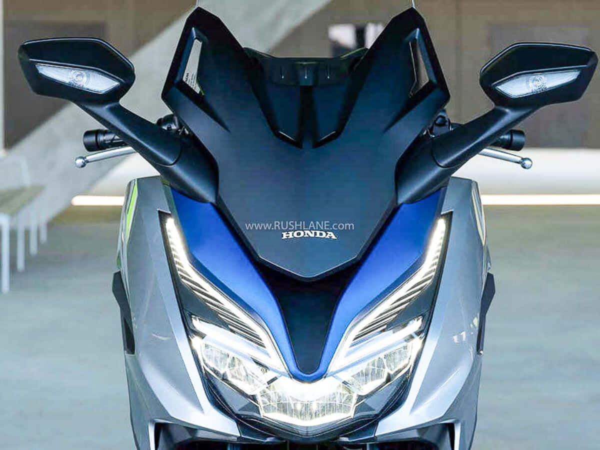 scooter 桌布 壁紙 — 一部時尚的藍銀色本田機車，配備銳利的LED頭燈和稜角分明的車身，在現代室內環境中展示。