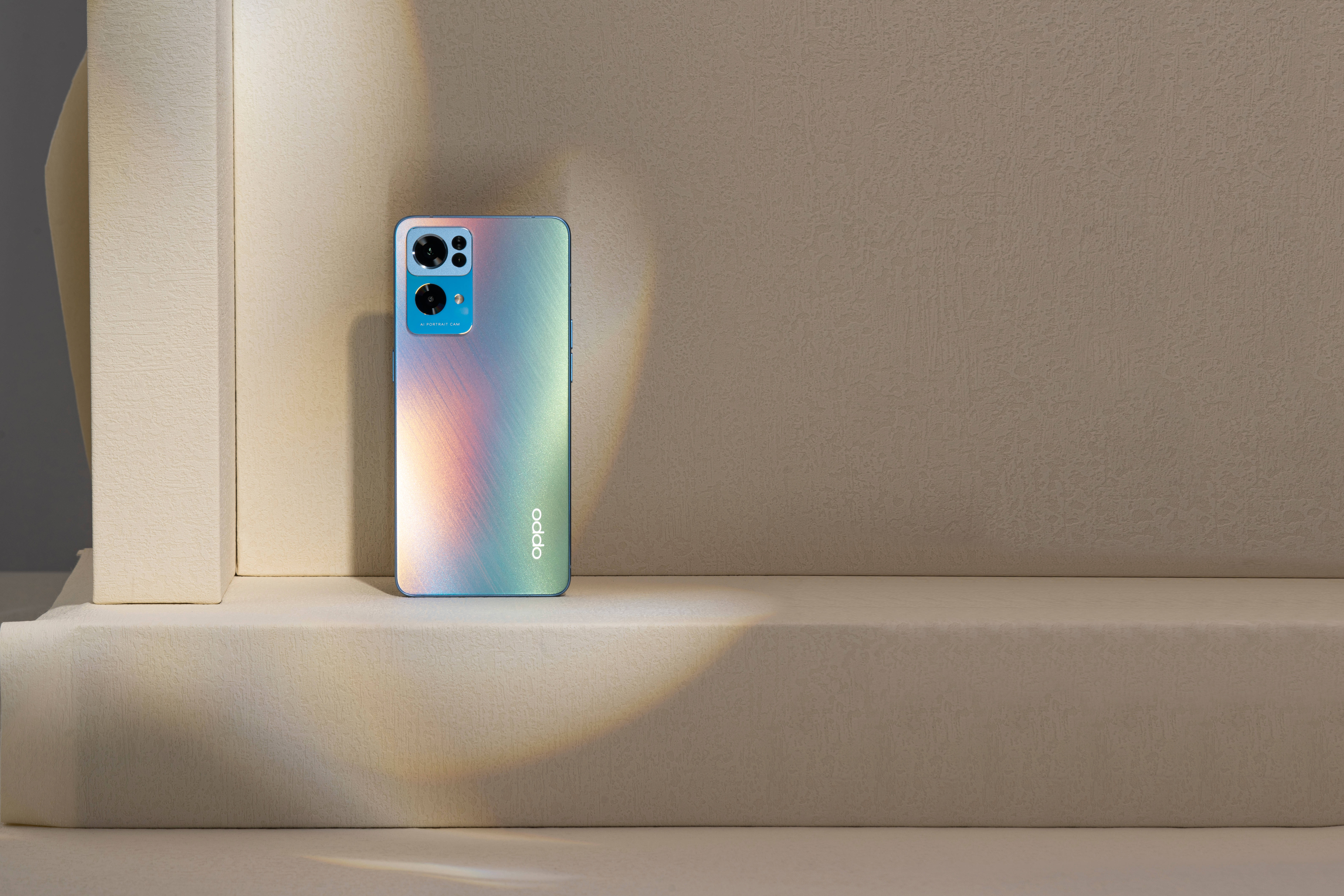 oppo 桌布 壁紙 — 一部時尚的虹彩藍色智慧型手機放在簡約的米色窗台上，沐浴在柔和的方向光中。