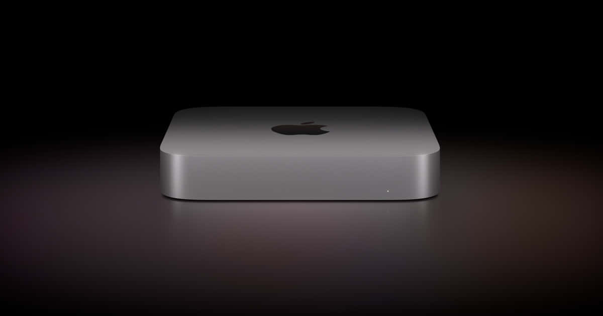 Mac 桌布 壁紙 — 一部時尚的銀色 Apple Mac mini 在戲劇性的工作室燈光下，居中放置在深色反光表面上。