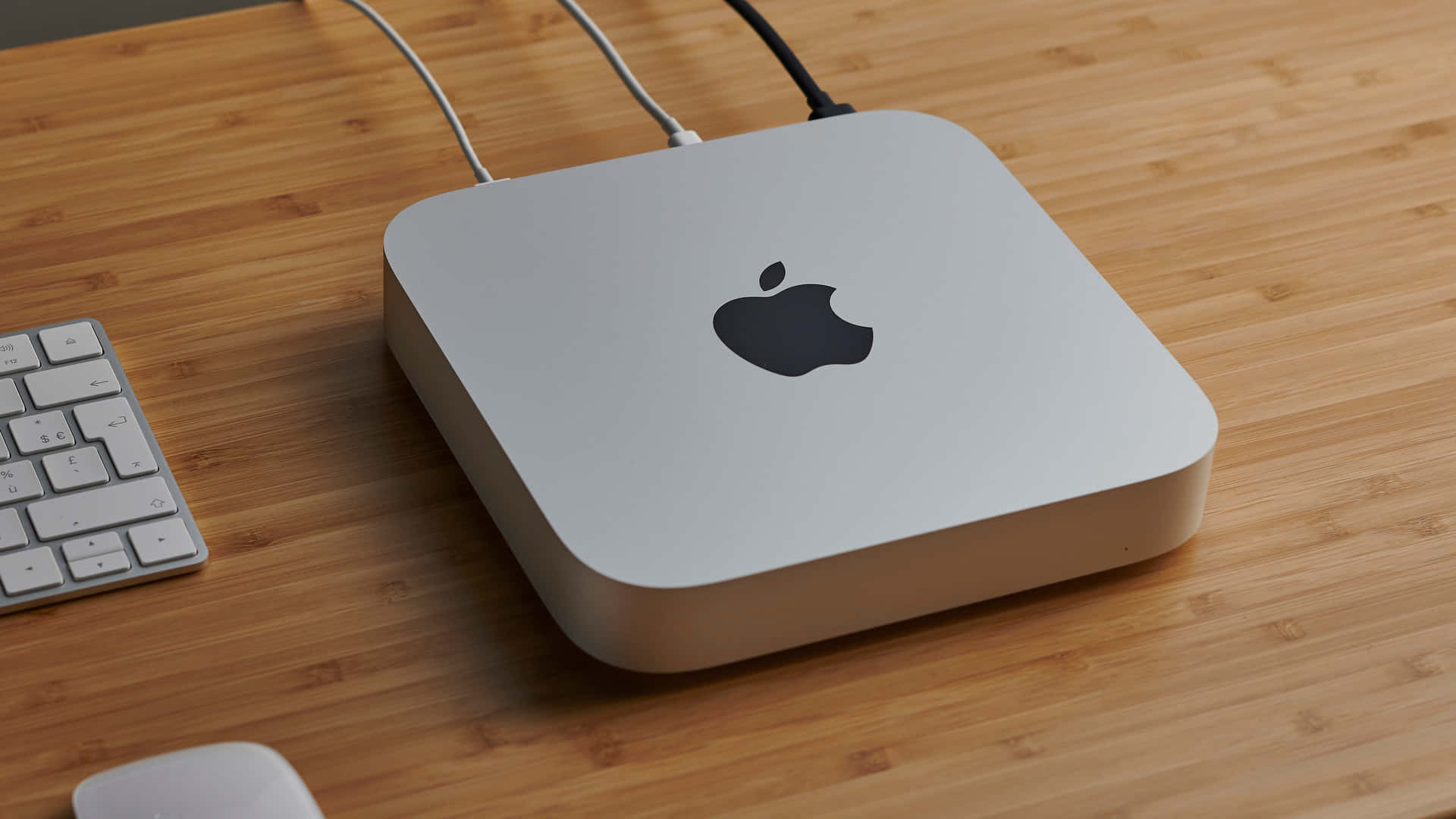 Mac 桌布 壁紙 — 一部時尚的銀色 Apple Mac mini 放置在溫暖的竹桌上，旁邊有相配的鍵盤和滑鼠。