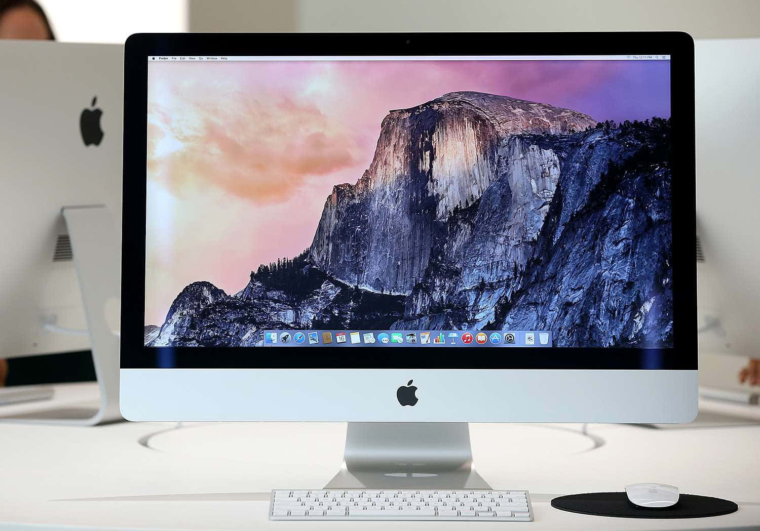 Mac 桌布 壁紙 — 一部時尚的銀色 iMac 顯示了 Half Dome 上充滿活力的日落，底部有 macOS Dock。