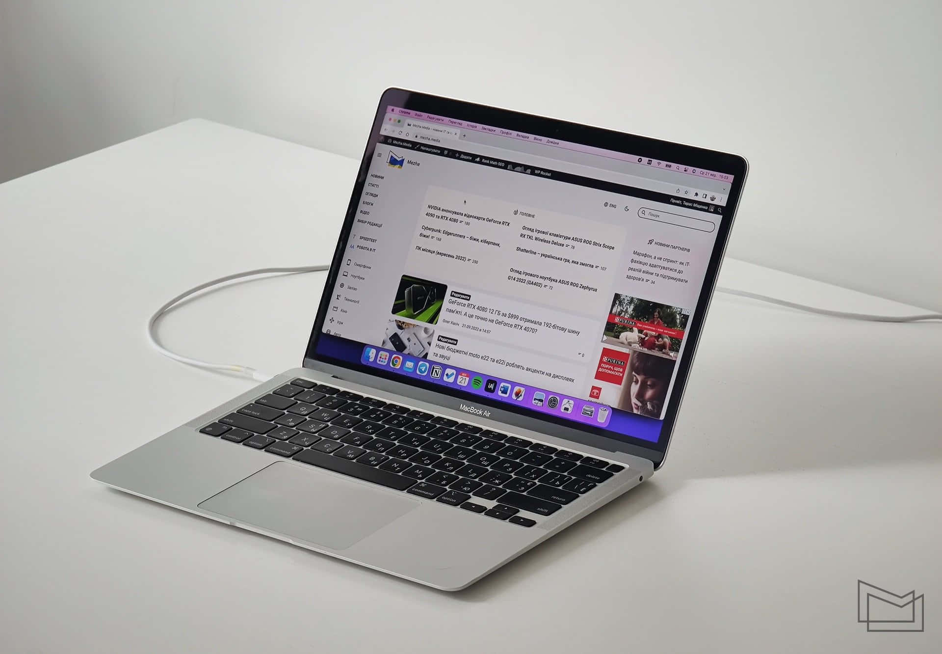 MacBook 動態圖片 桌布 壁紙 — 一部時尚的銀色 MacBook Air 打開放在白色桌子上，顯示帶有西里爾文字和產品圖片的網頁瀏覽器。