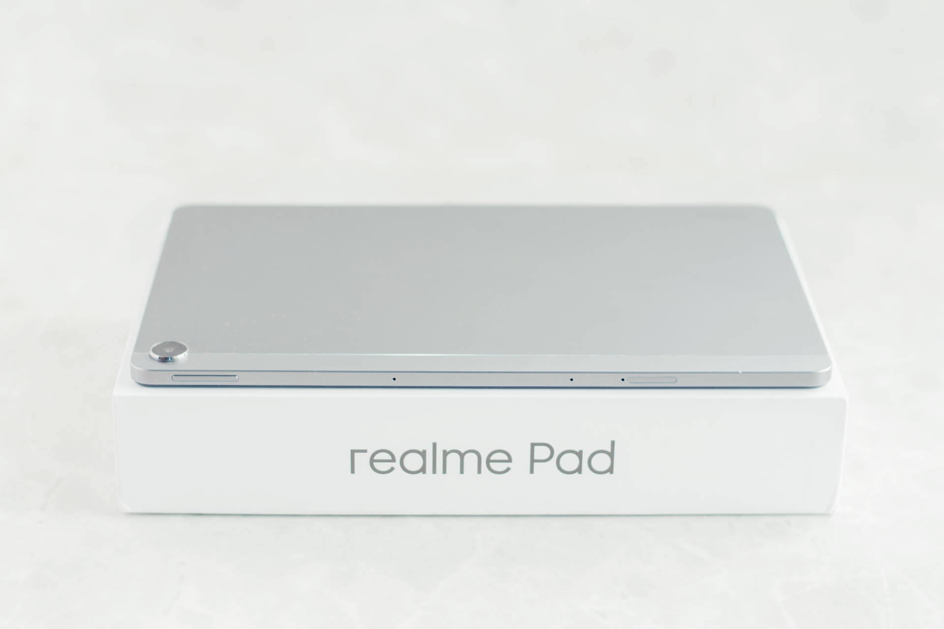 銀色 realme Pad 平板電腦放在白色盒子上，設計簡約。