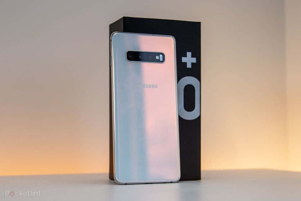 Galaxy S10 桌布 壁紙 — 一部時尚的銀色Samsung智慧型手機直立在其帶有加號符號的黑色盒子旁邊，背景是柔和照明的漸變色。