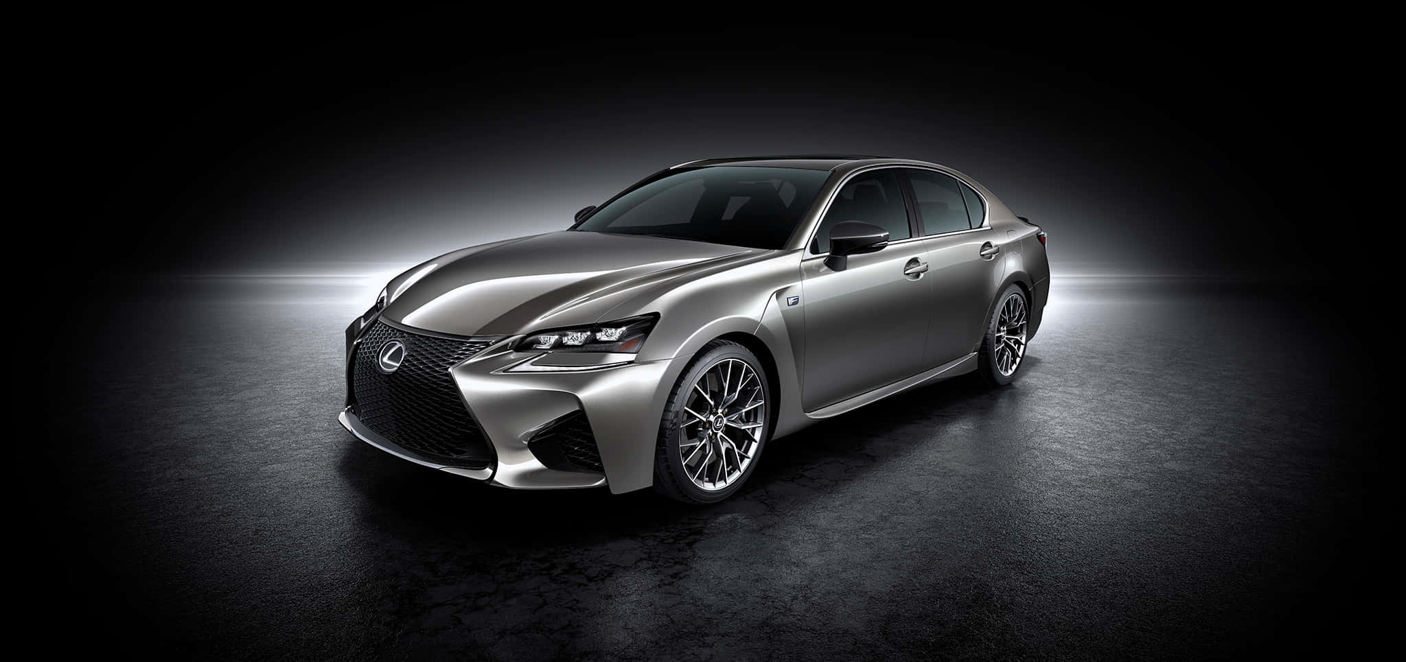 Lexus Gs F 桌布 壁紙 — 一部時尚的銀色凌志轎車在戲劇性的攝影棚燈光下，在深色紋理地板上閃閃發光。