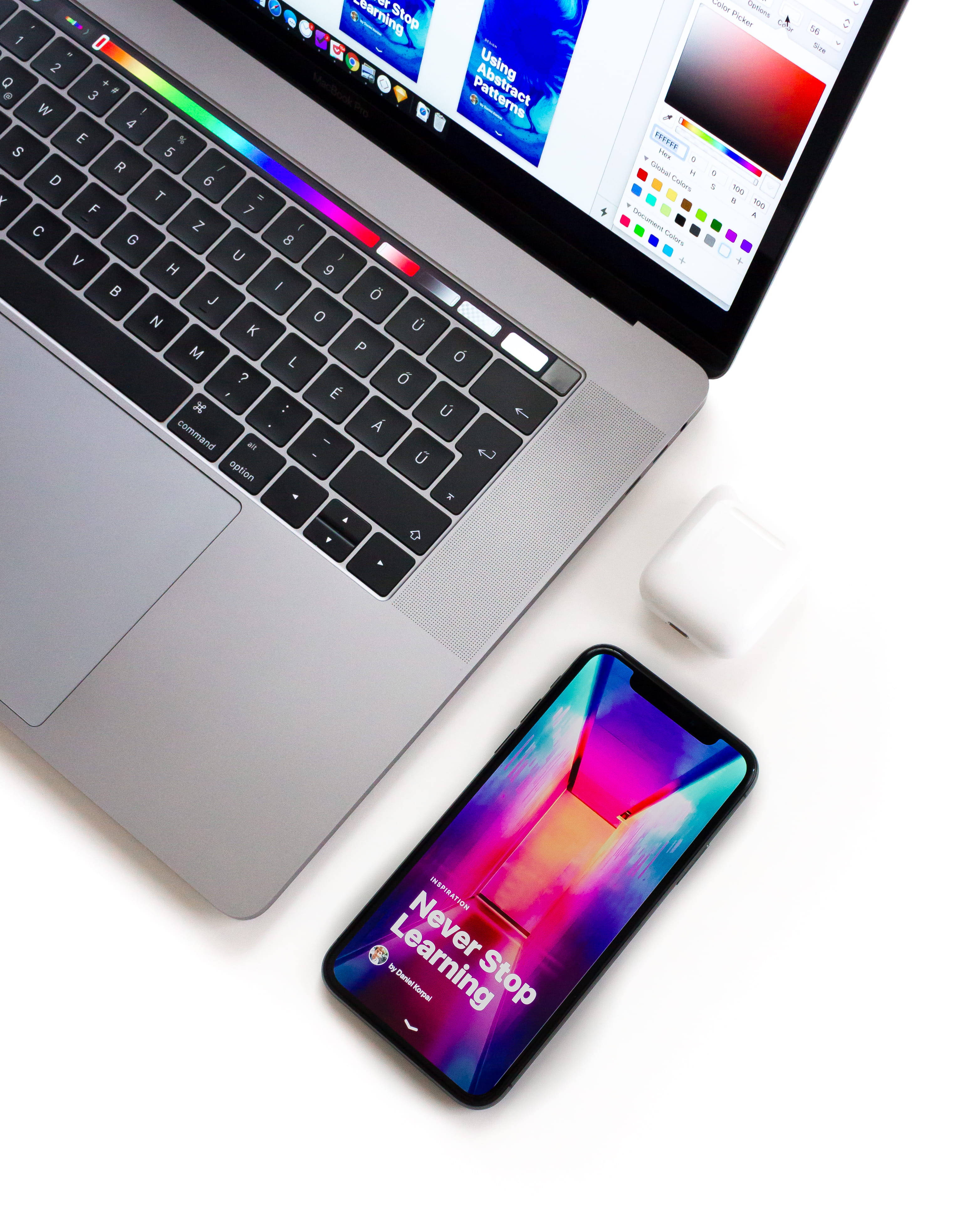 MacBook 動態圖片 桌布 壁紙 — 一部時尚的銀色筆記型電腦和智慧型手機，帶有鮮豔的漸變螢幕，放置在潔白的表面上，展示現代科技工作空間。