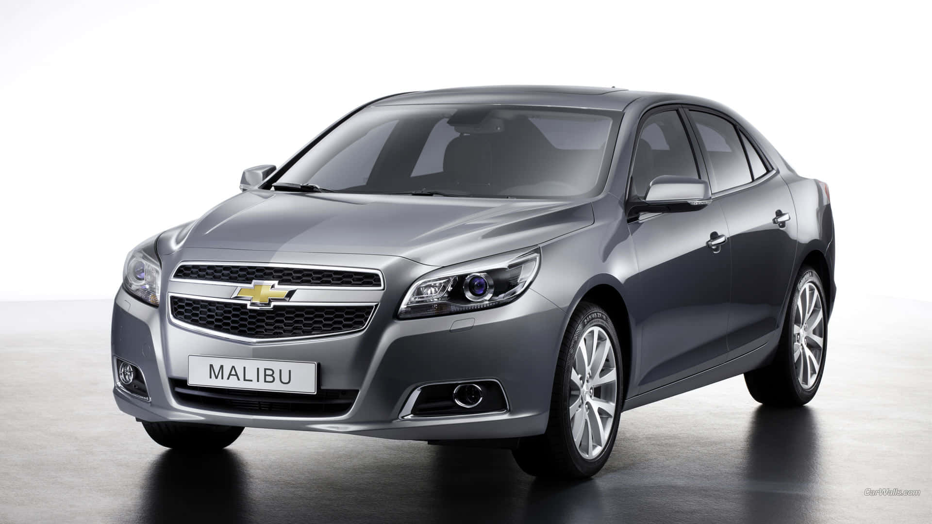 chevy 桌布 壁紙 — 一部時尚的銀色雪佛蘭 Malibu 轎車在簡約風格的攝影棚中展示，配有反射地板和明亮燈光。