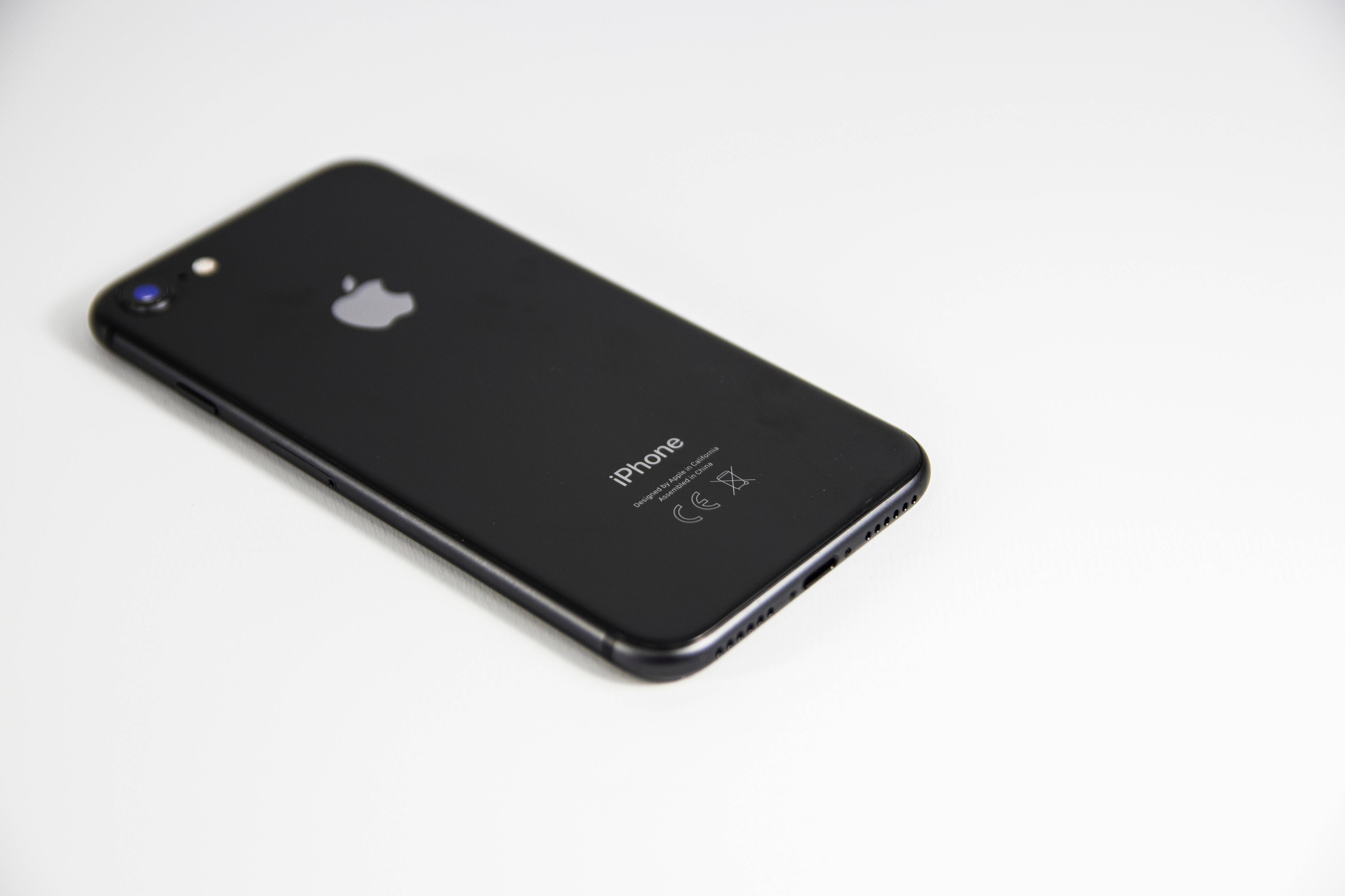 iPhone 鎖定畫面 桌布 壁紙 — 一部時尚的黑色 iPhone 7 對角放置在潔白的表面上，柔和的光線突顯其光澤質感。