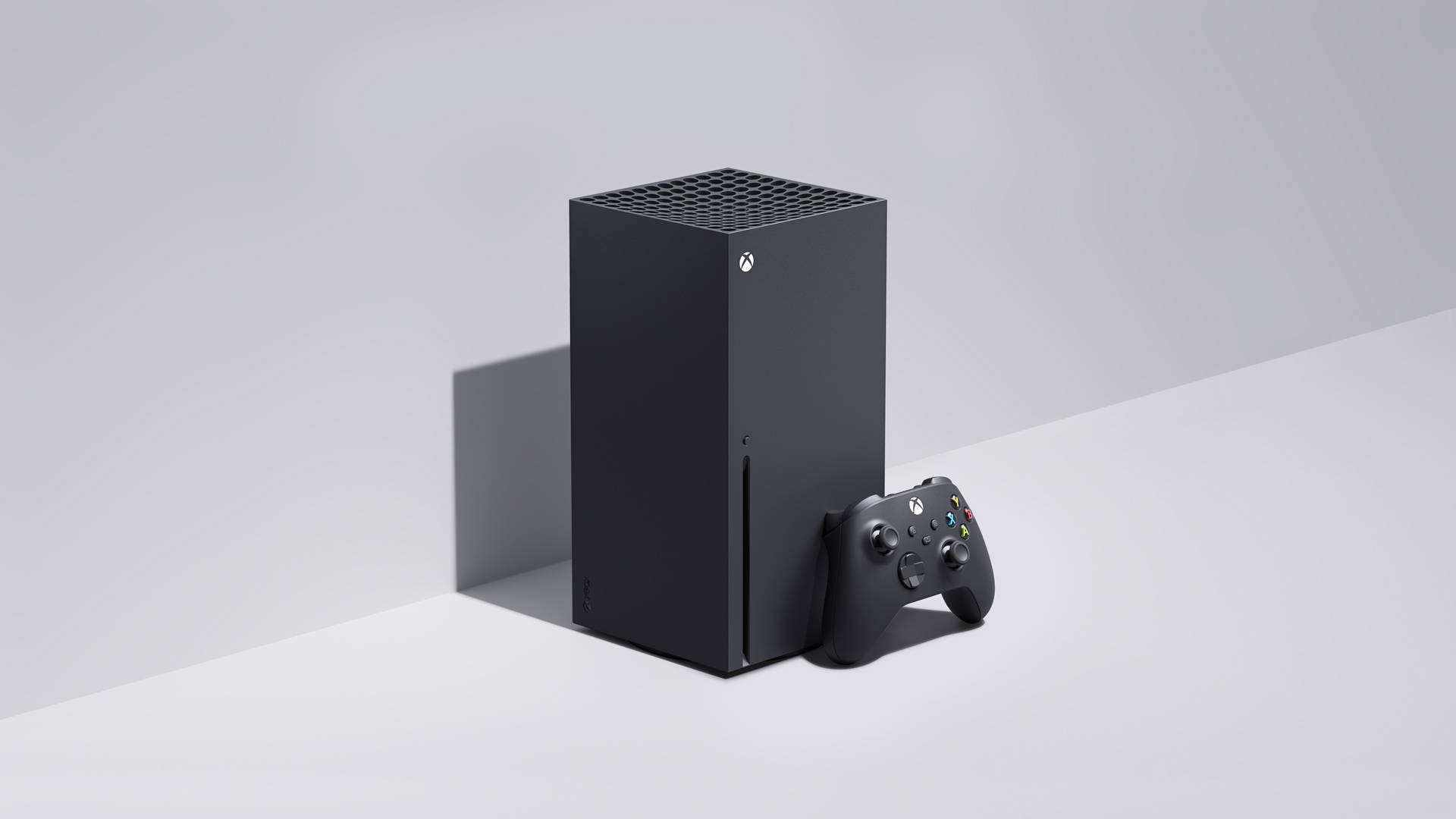 Xbox 桌布 壁紙 — 一部時尚的黑色 Xbox Series X 主機和手把放在簡約的白色表面上，帶有柔和陰影。