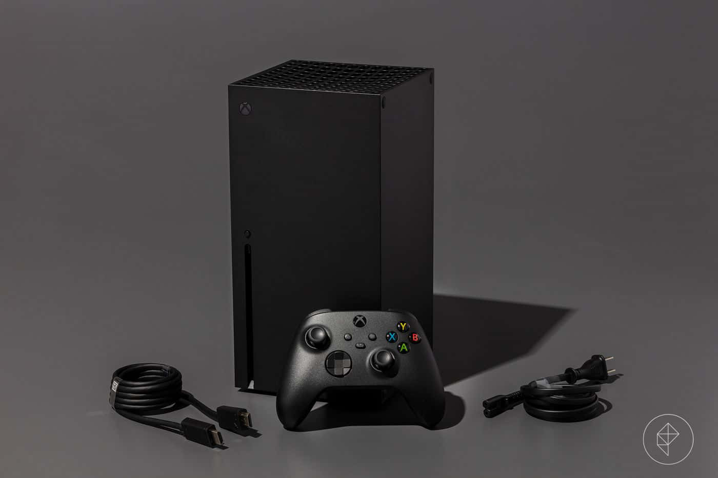 Xbox 桌布 壁紙 — 一部時尚的黑色 Xbox Series X 主機和手把放在灰色表面上，旁邊整齊地纏繞著電線。