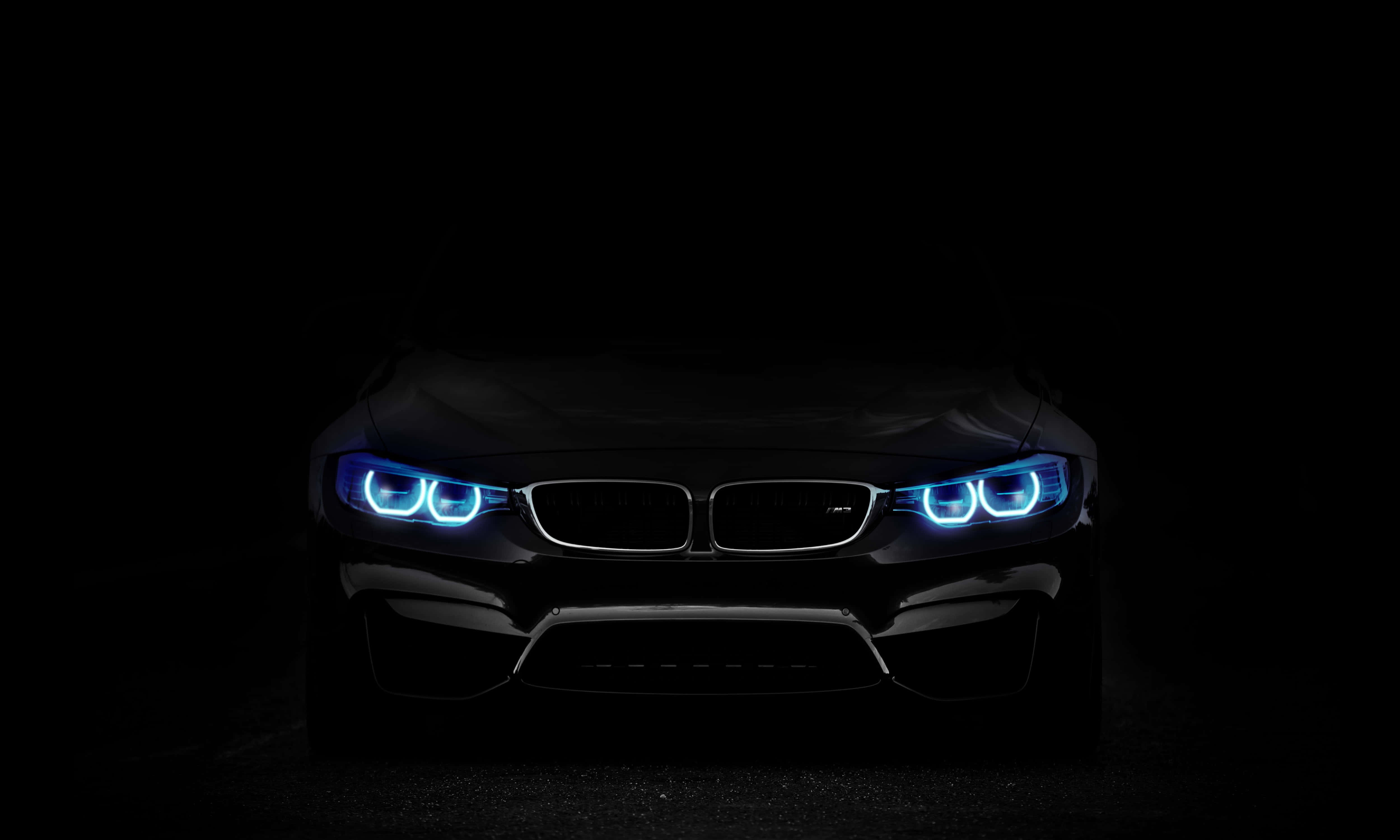 跑車 桌布 壁紙 — 一部時尚的黑色BMW跑車在漆黑背景下散發出充滿活力的藍色頭燈光芒。