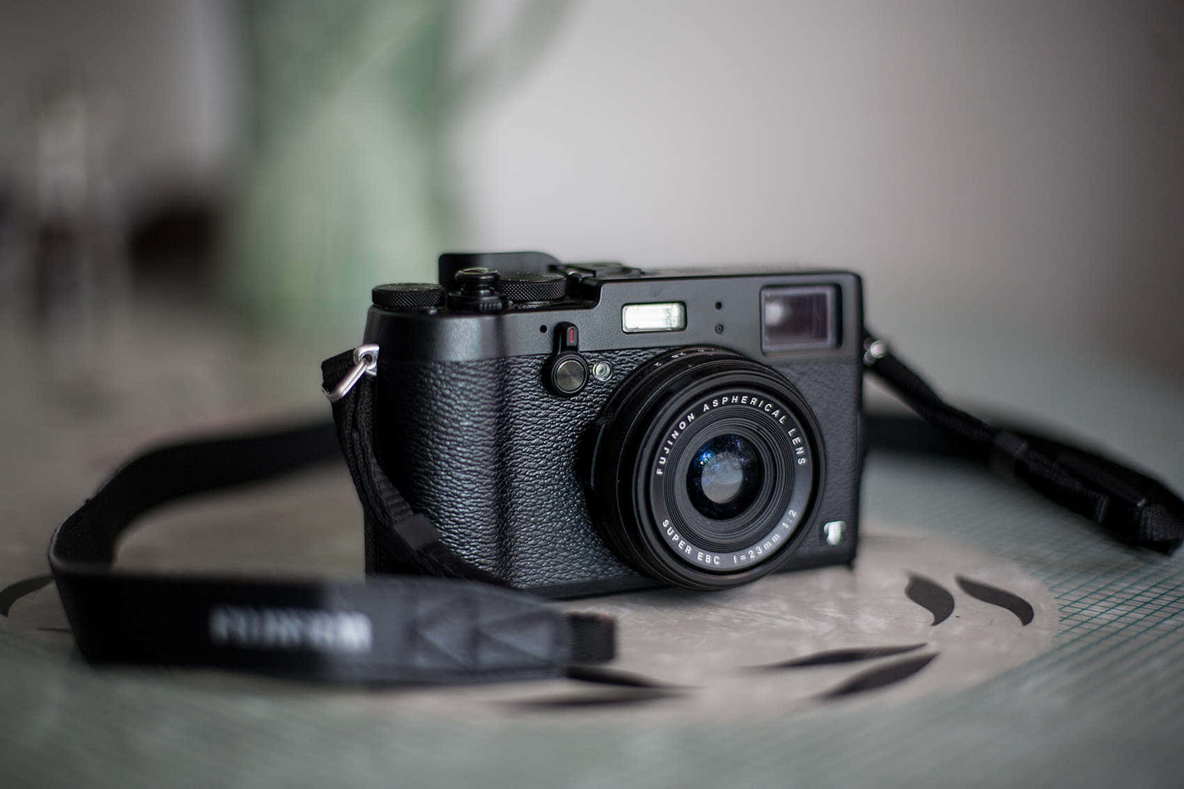 相機 桌布 壁紙 — 一部時尚的黑色Fujifilm X-T30相機放置在紋理表面上，背景是模糊的綠色。