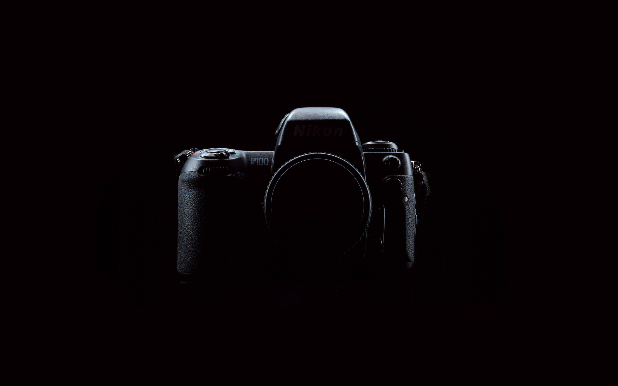 相機 桌布 壁紙 — 一部時尚的黑色Nikon F100相機機身，在漆黑背景中微微發光。