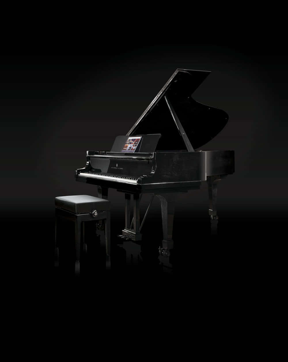 Black And White Piano 桌布 壁紙 — 一部時尚的黑色三角鋼琴，打開琴蓋，配以相配的琴凳，在柔和的聚光燈下，戲劇性地矗立在深色背景前。