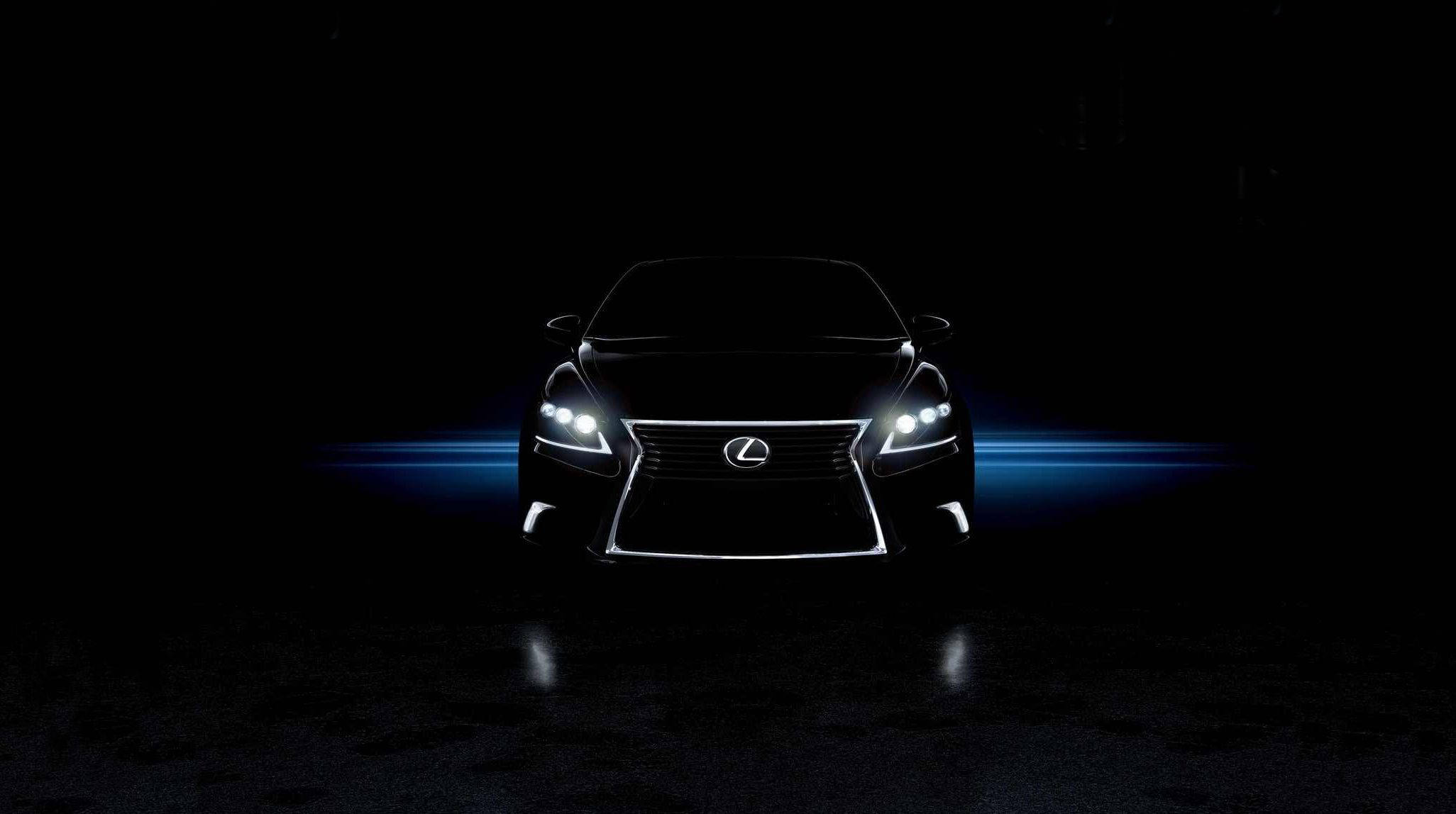 Lexus 標誌 桌布 壁紙 — 一部時尚的黑色凌志房車，在漆黑背景下閃耀著銳利的白色頭燈和藍色光條。
