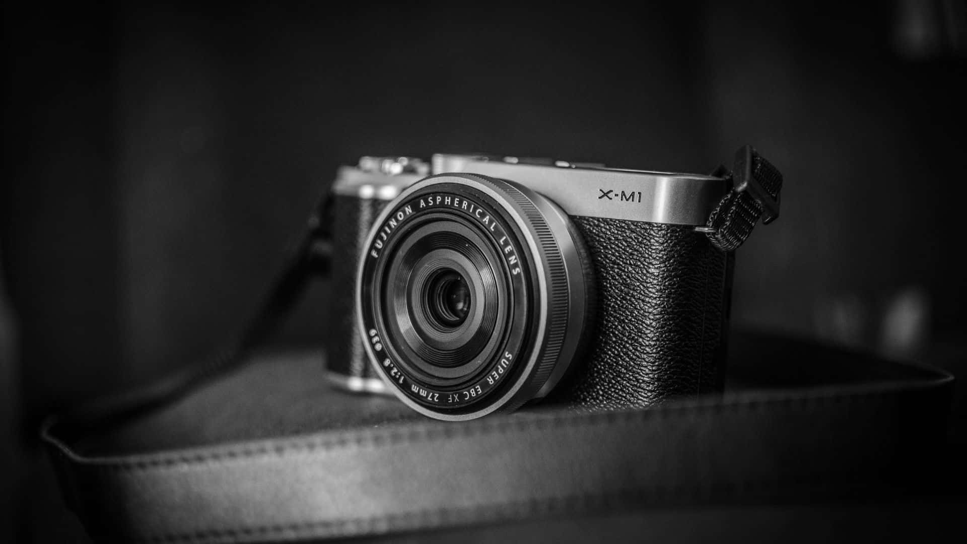 攝影師 桌布 壁紙 — 一部時尚的黑色和銀色 Fujifilm X-M1 相機放置在紋理皮革表面上，景深較淺。