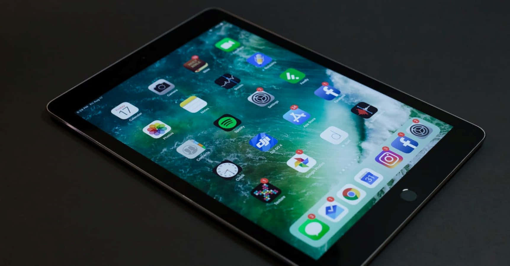 iPad 桌布 壁紙 — 一部時尚的黑色平板電腦顯示充滿活力的綠色海洋桌布，螢幕上排列著應用程式圖示。
