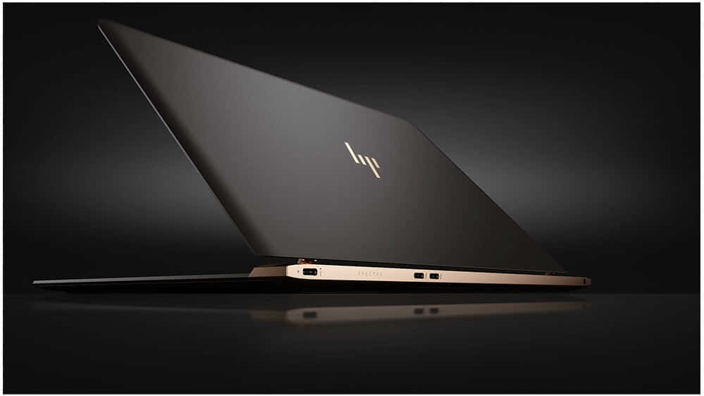 HP 桌布 壁紙 — 一部時尚的黑色筆記型電腦，帶有金色飾邊和發光標誌，傾斜放置在深色反光表面上。