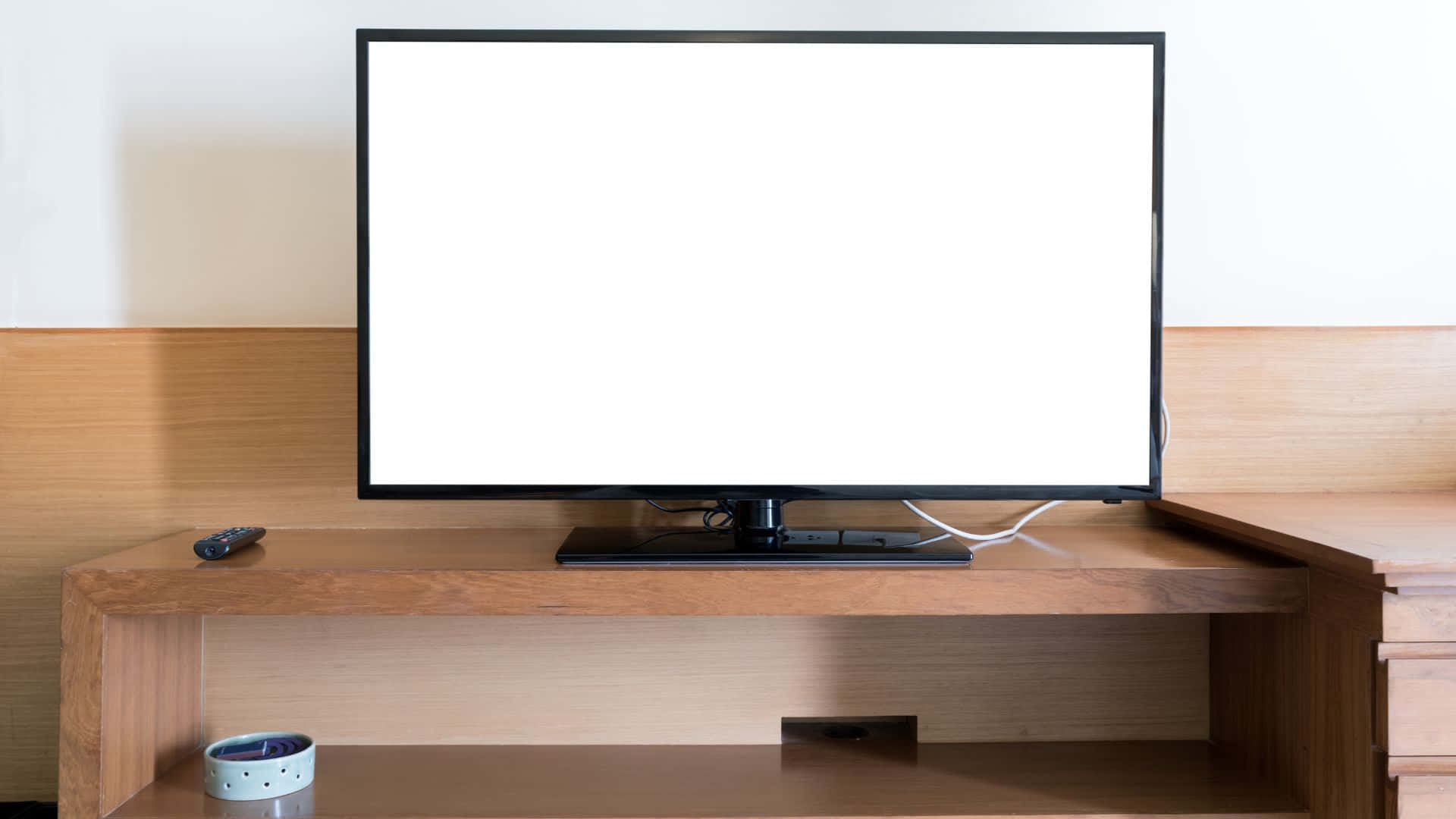 Computer Screen 桌布 壁紙 — 一部時尚的黑色電視機，帶有空白白色螢幕，居中放置在淺色木質媒體櫃上，下方有遙控器和時鐘。
