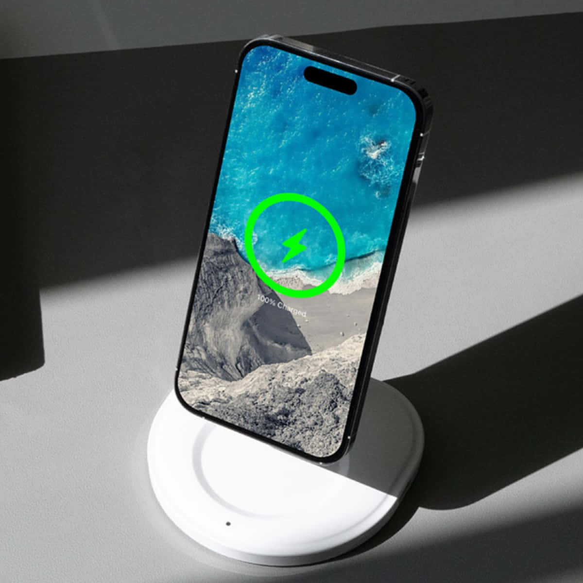 Wireless Charging 桌布 壁紙 — 一部智慧型手機在白色無線充電器上顯示充滿活力的海洋桌布，帶有綠色充電圖示和「100% 已充電」文字。