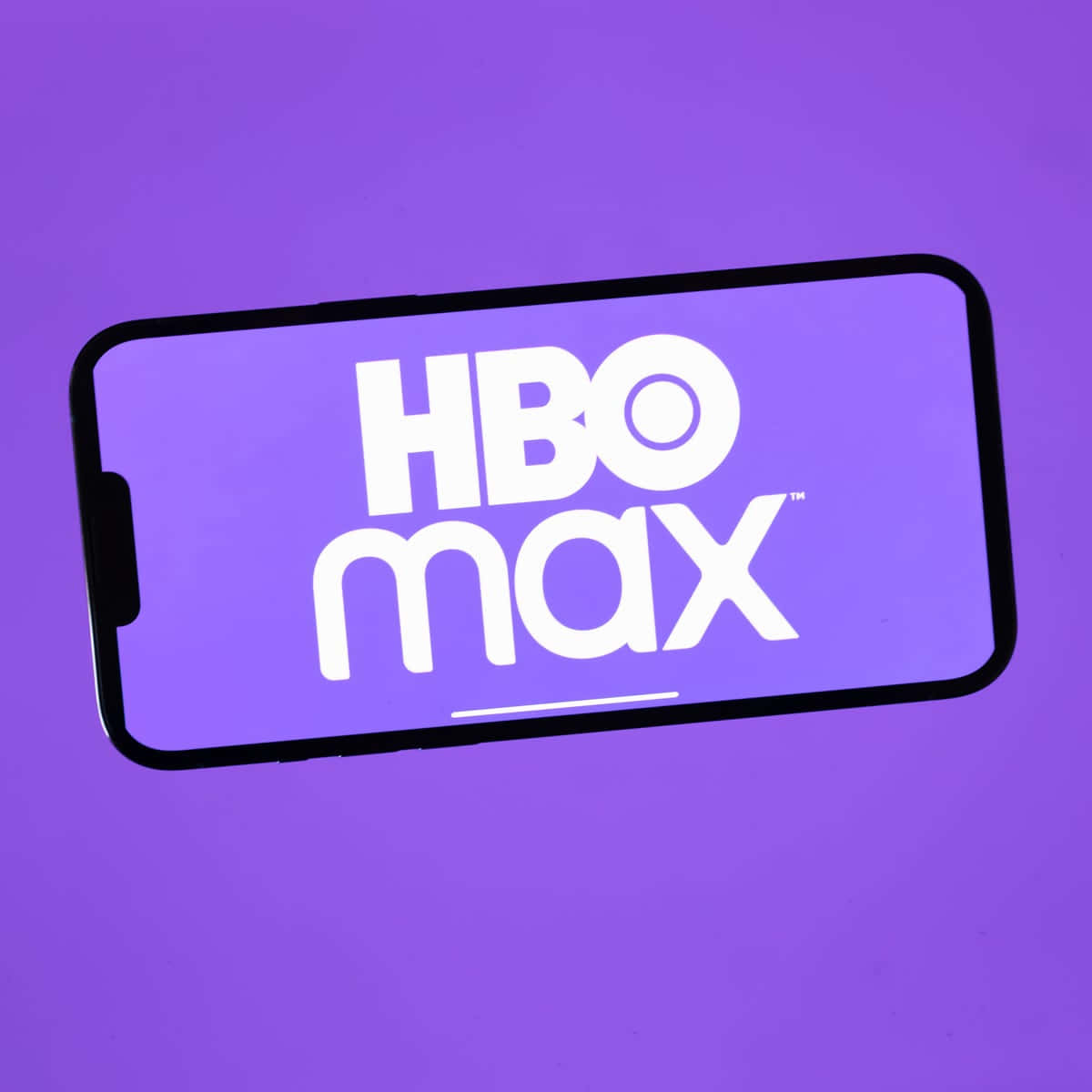 HBO 桌布 壁紙 — 一部智慧型手機在純紫色背景上以粗體白色文字顯示HBO Max標誌。