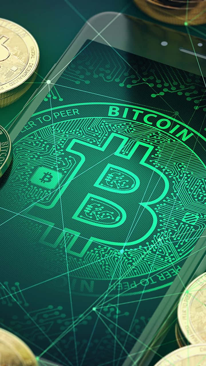 加密貨幣 桌布 壁紙 — 一部智慧型手機在電路上顯示發光的綠色Bitcoin標誌，周圍散落著實體金幣。