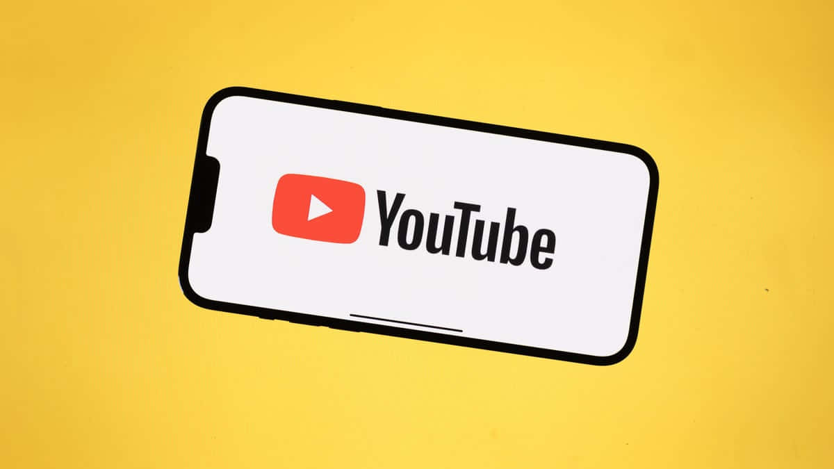 YouTube 桌布 壁紙 — 一部智慧型手機在鮮黃色背景上顯示 YouTube 標誌。