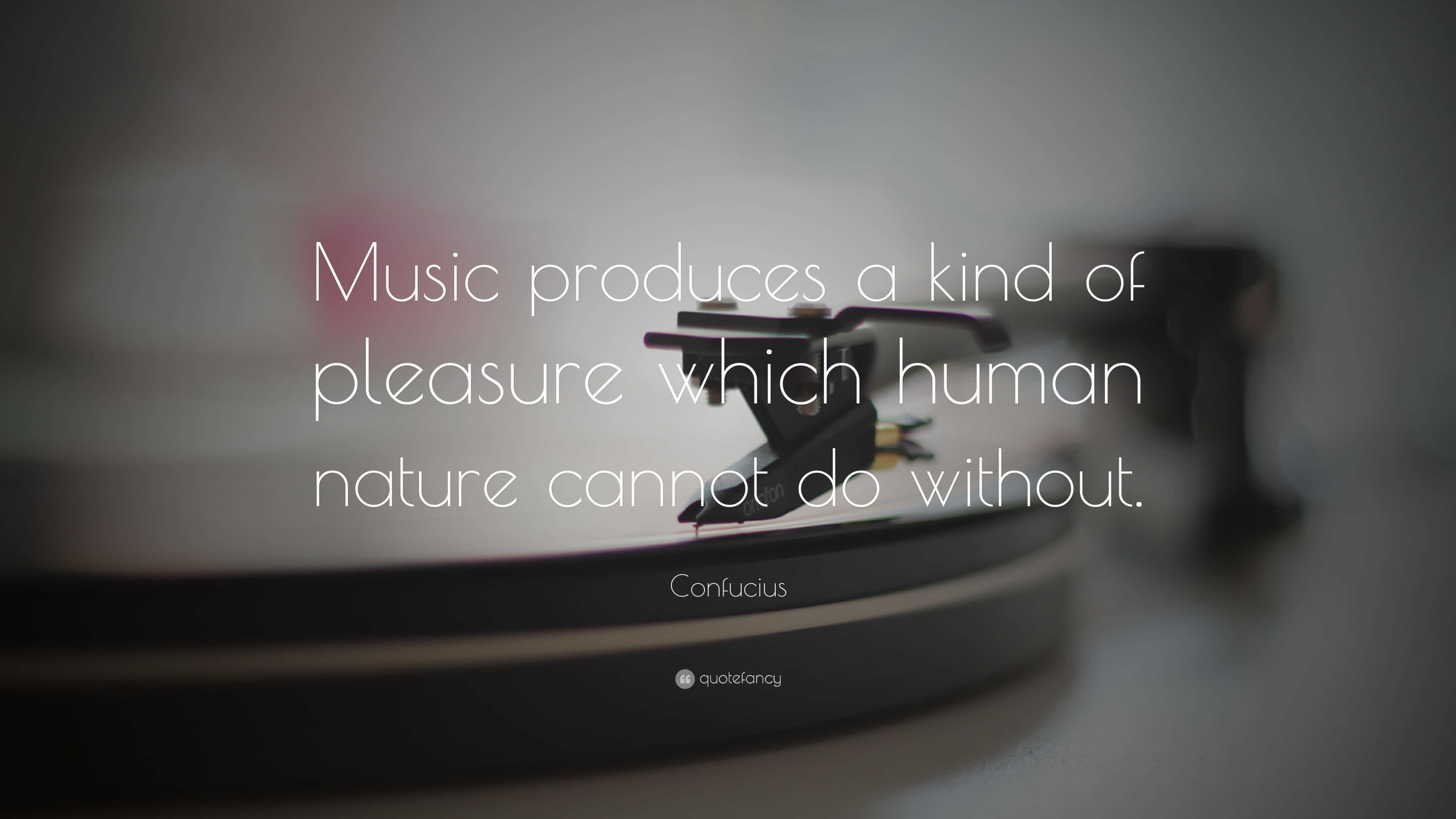 Inspirational Quotes 桌布 壁紙 — 一部模糊的黑膠唱片機，上面覆蓋著一句關於音樂本質樂趣的引文，歸因於孔子。
