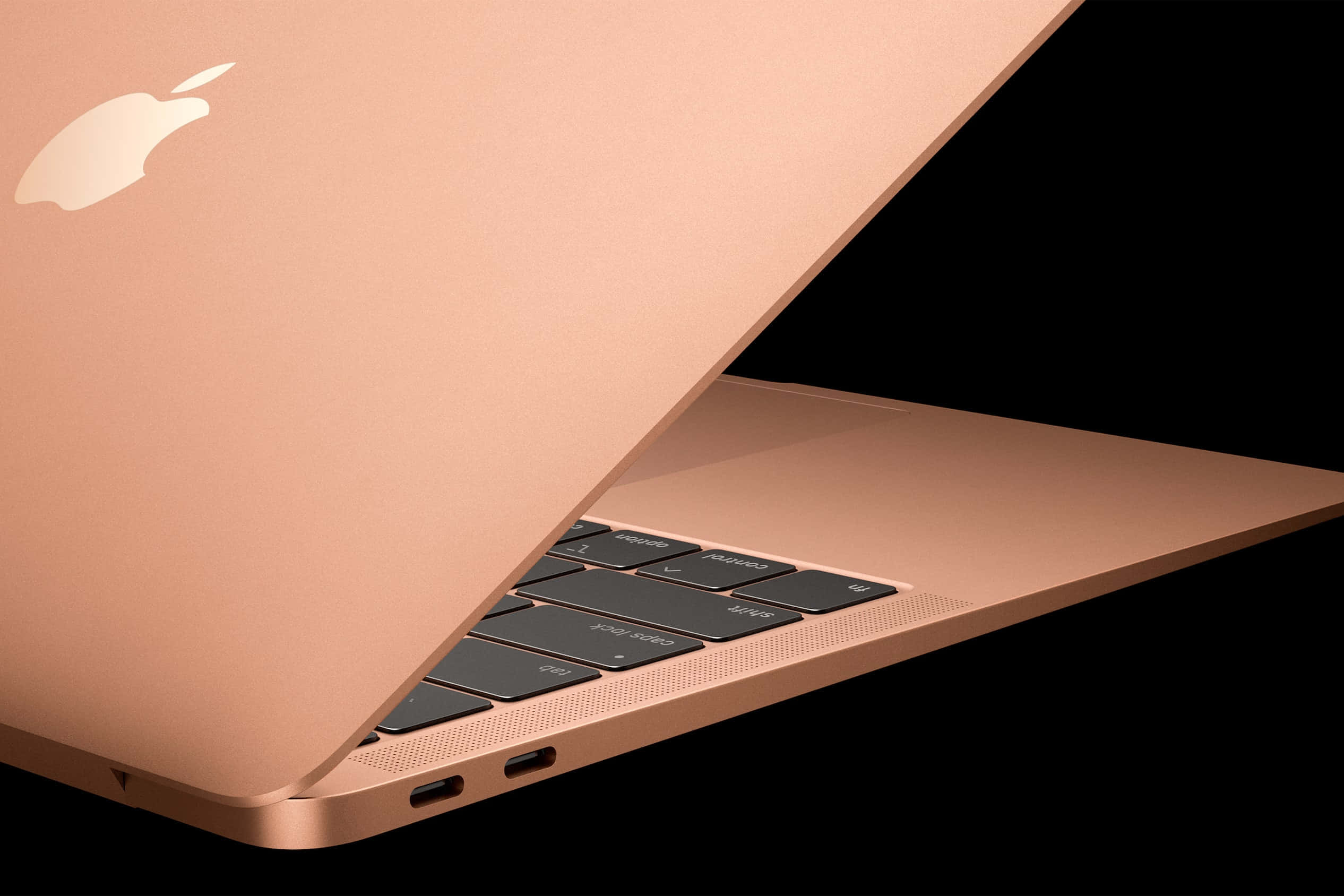 MacBook 動態圖片 桌布 壁紙 — 一部流線型玫瑰金色 MacBook 筆記型電腦斜向打開，在純黑背景上展示其鍵盤和標誌。