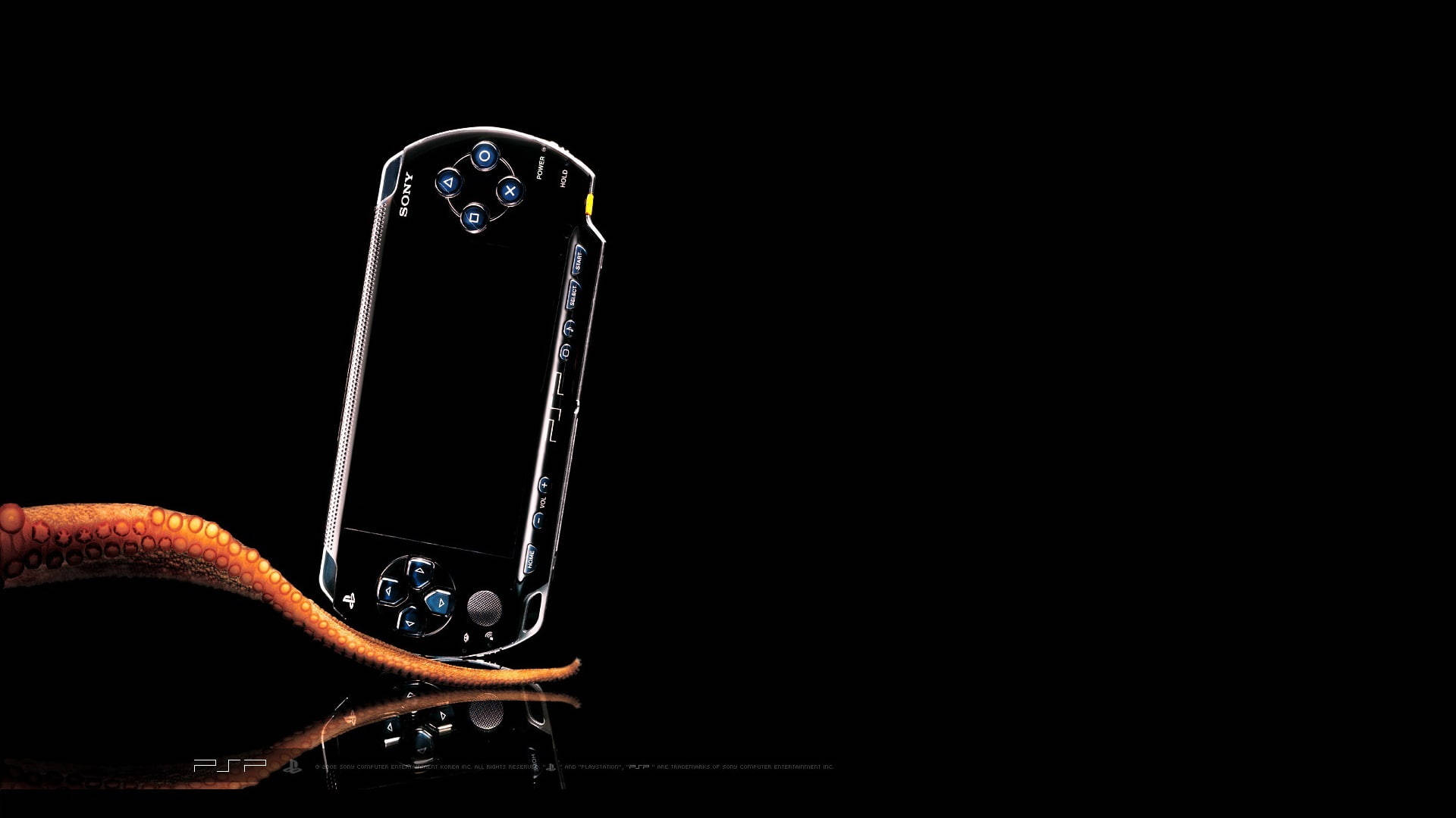 PlayStation 桌布 壁紙 — 一部流線型銀色 PSP 主機直立於反光黑色表面上，下方有一條橙色章魚觸手蜷曲。