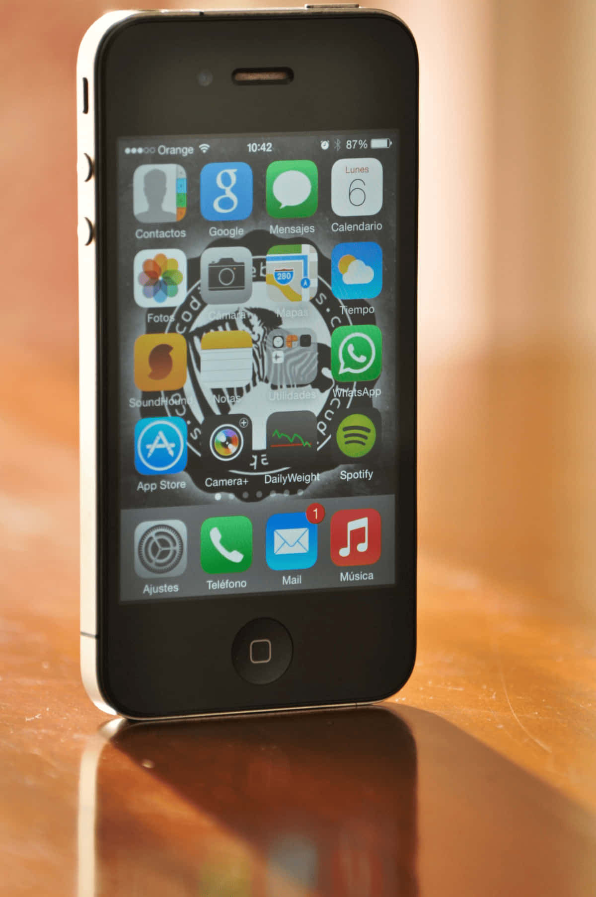 手機 桌布 壁紙 — 一部白色iPhone 4s直立於溫暖的木質表面上，顯示其主螢幕，帶有應用程式圖示和87%的電池電量。