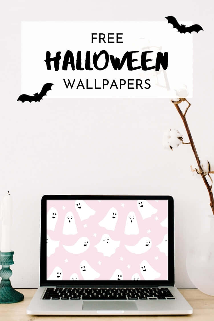 Pastel Halloween 桌布 壁紙 — 一部筆記型電腦顯示可愛鬼魂桌布，粉紅色背景，蝙蝠和棉花枝條裝飾著簡約的桌面設置。