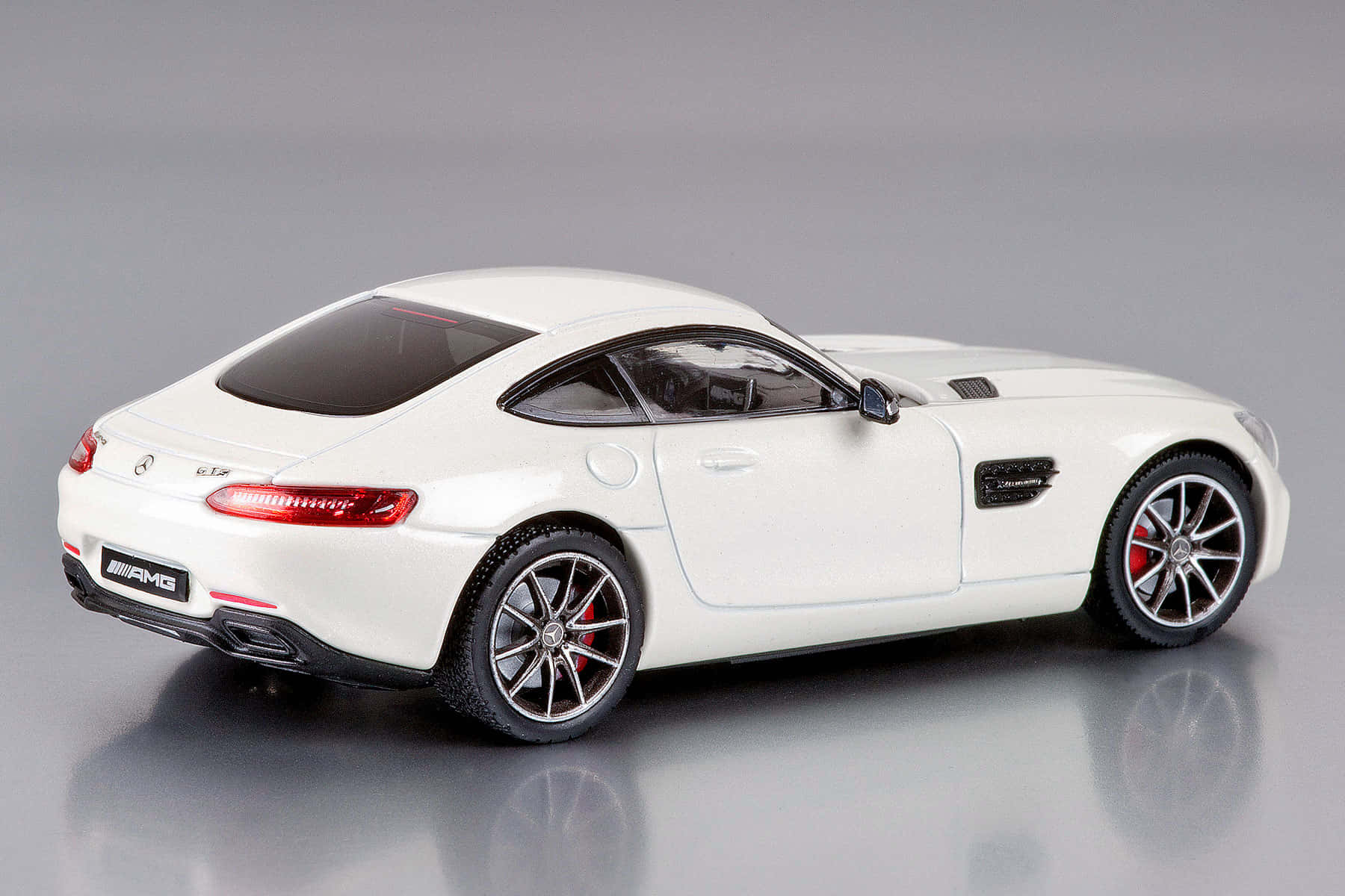 Car Model 桌布 壁紙 — 一部純白色AMG跑車模型，配備紅色制動卡鉗和時尚合金輪圈，在攝影棚燈光下拍攝於反光灰色表面。