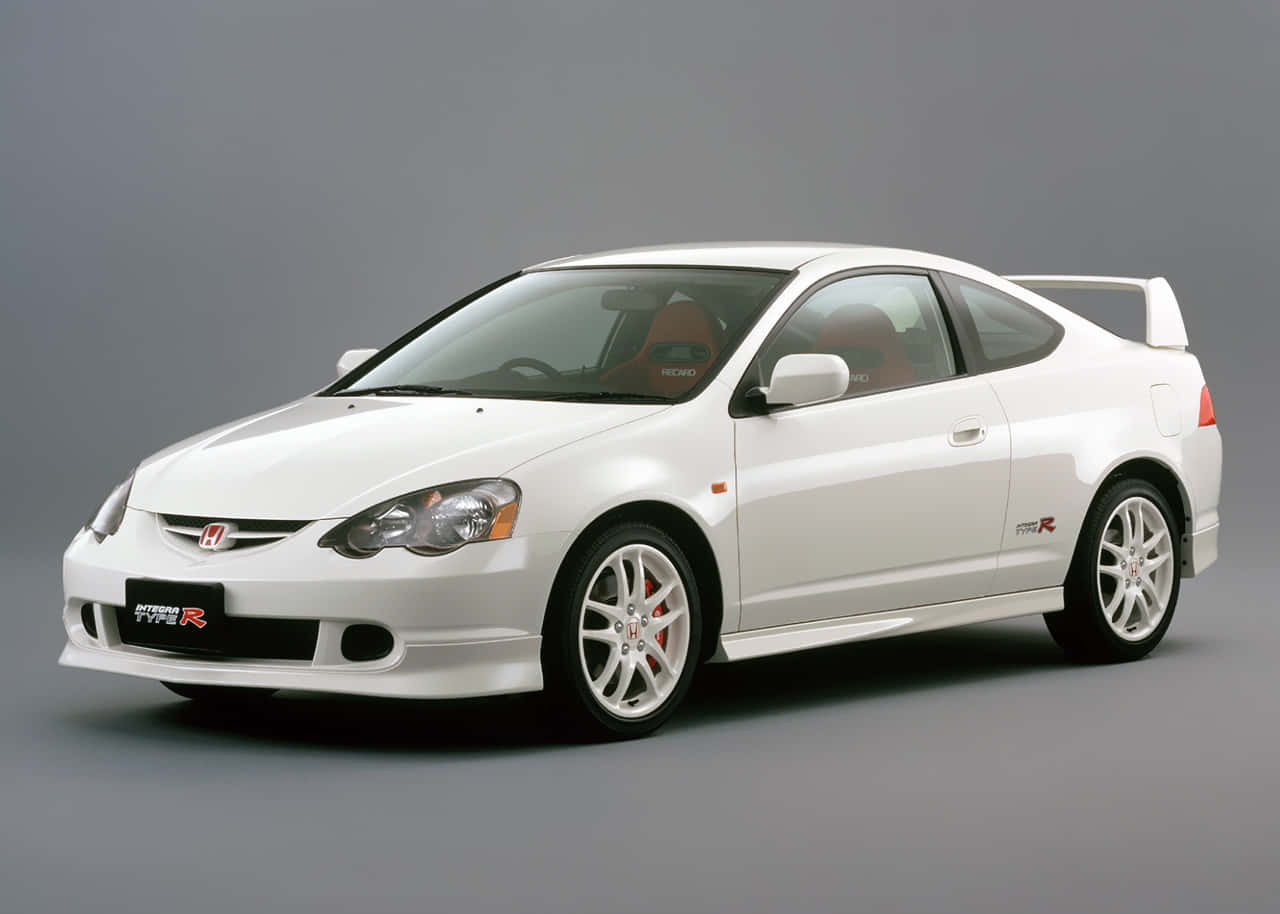 Honda Integra 桌布 壁紙 — 一部純白色的本田Integra Type R運動轎跑車，配備紅色內裝和後擾流板，置於中性灰色工作室背景前。