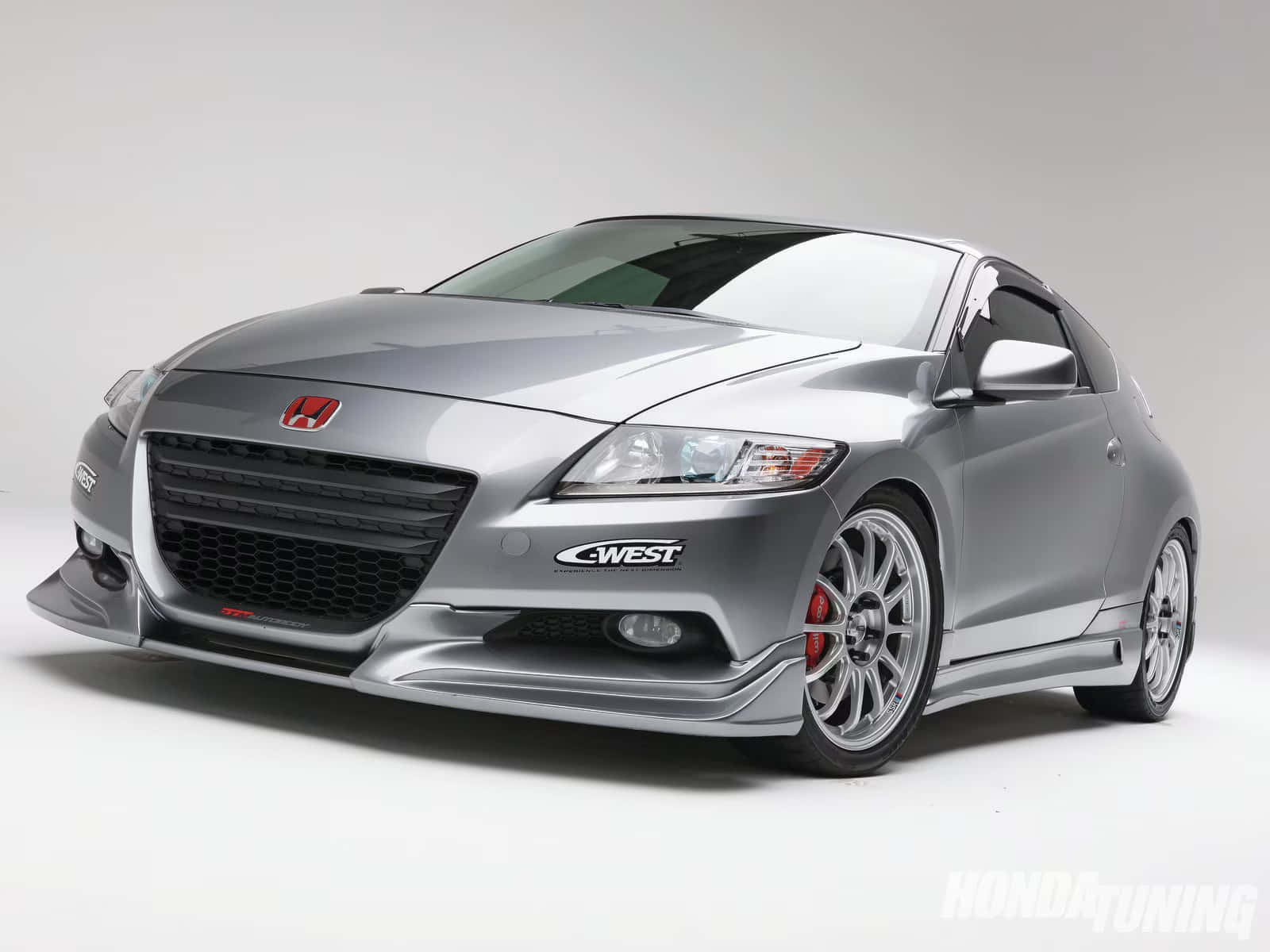 Honda Cr-z 桌布 壁紙 — 一部線條流暢的銀色本田轎跑車，配備客製化改裝零件和紅色制動卡鉗，在純白色工作室背景前擺拍。